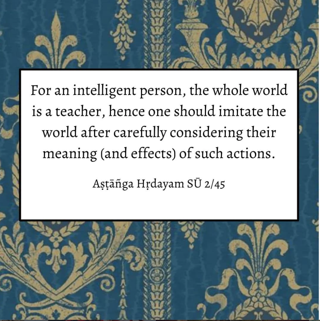 Quote on a decorative blue and gold floral background. The quote reads, "For an intelligent person, the whole world is a teacher, hence one should imitate the world after carefully considering their meaning (and effects) of such actions." - Aṣṭāṅga Hṛdayam Sū 2/45.