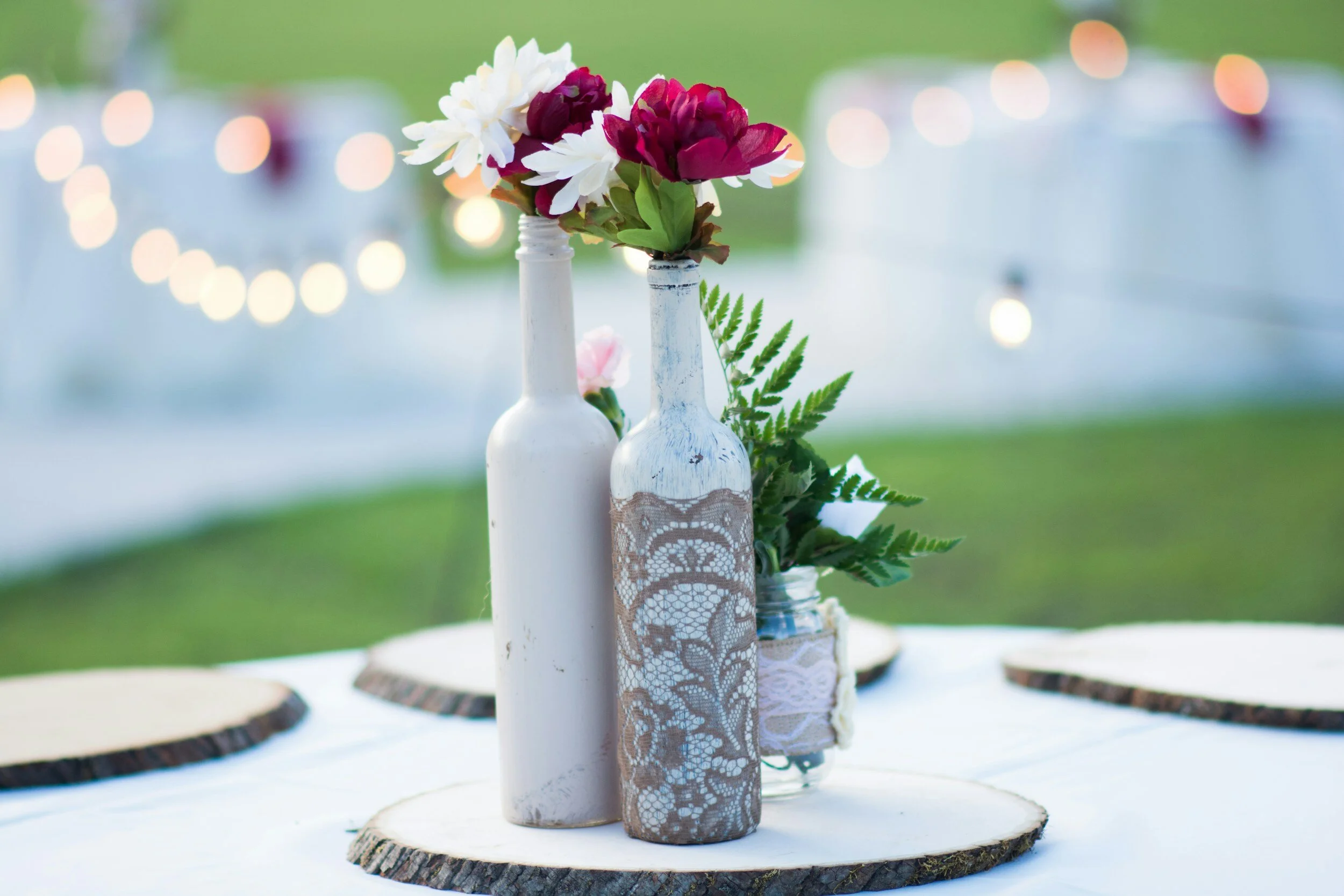 Decorative table setting with painted bottles and flowers on wooden slices