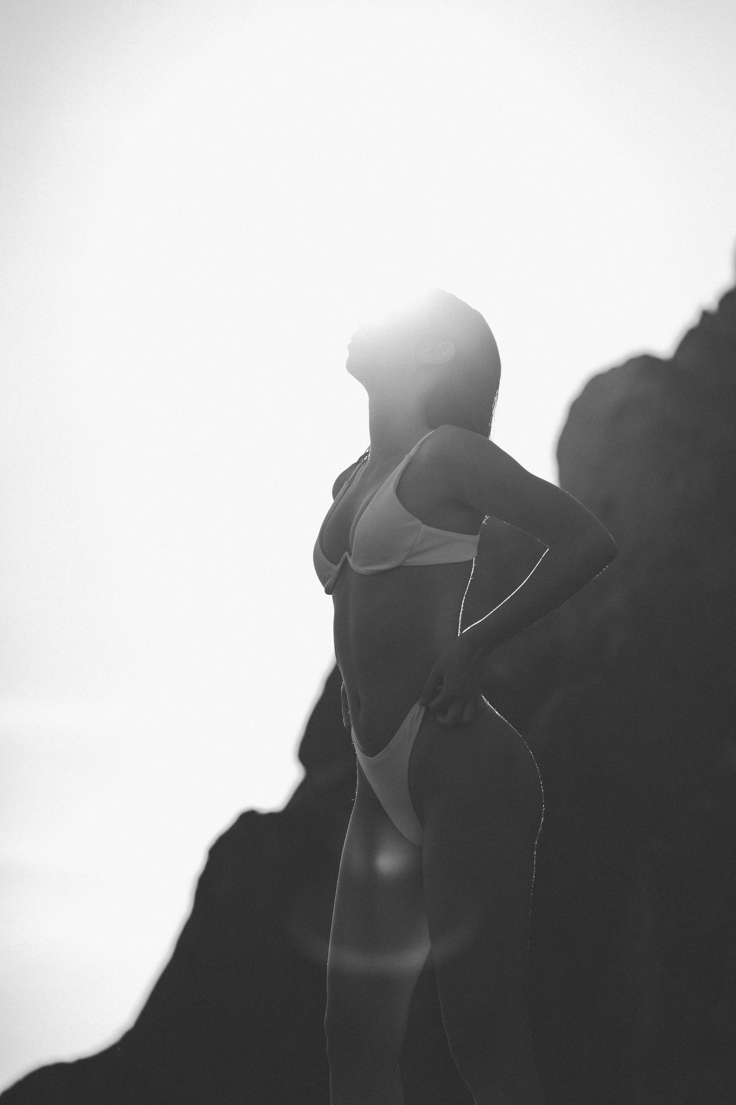 A woman standing outdoors on a mountain, facing upward with her eyes closed.