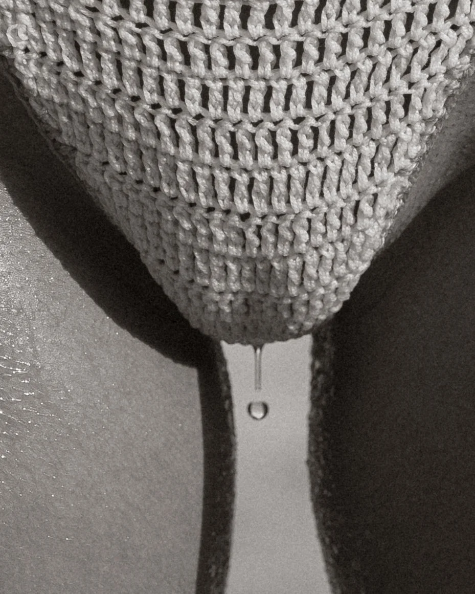 Close-up of a gray mesh fabric with water dripping from the tip.