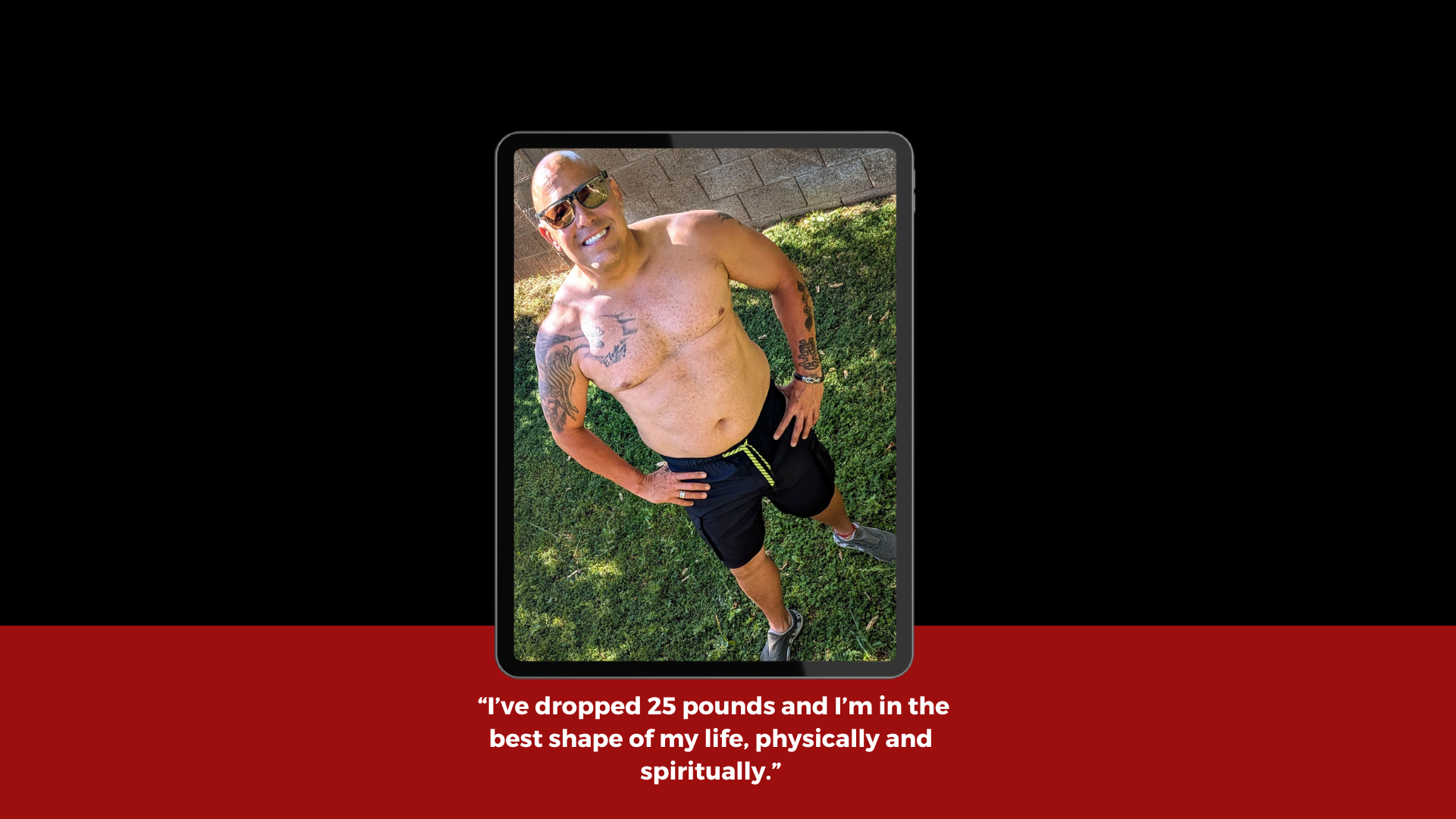 A shirtless man with sunglasses and tattoos on his arms standing outdoors on grass, smiling with his hands on his hips.