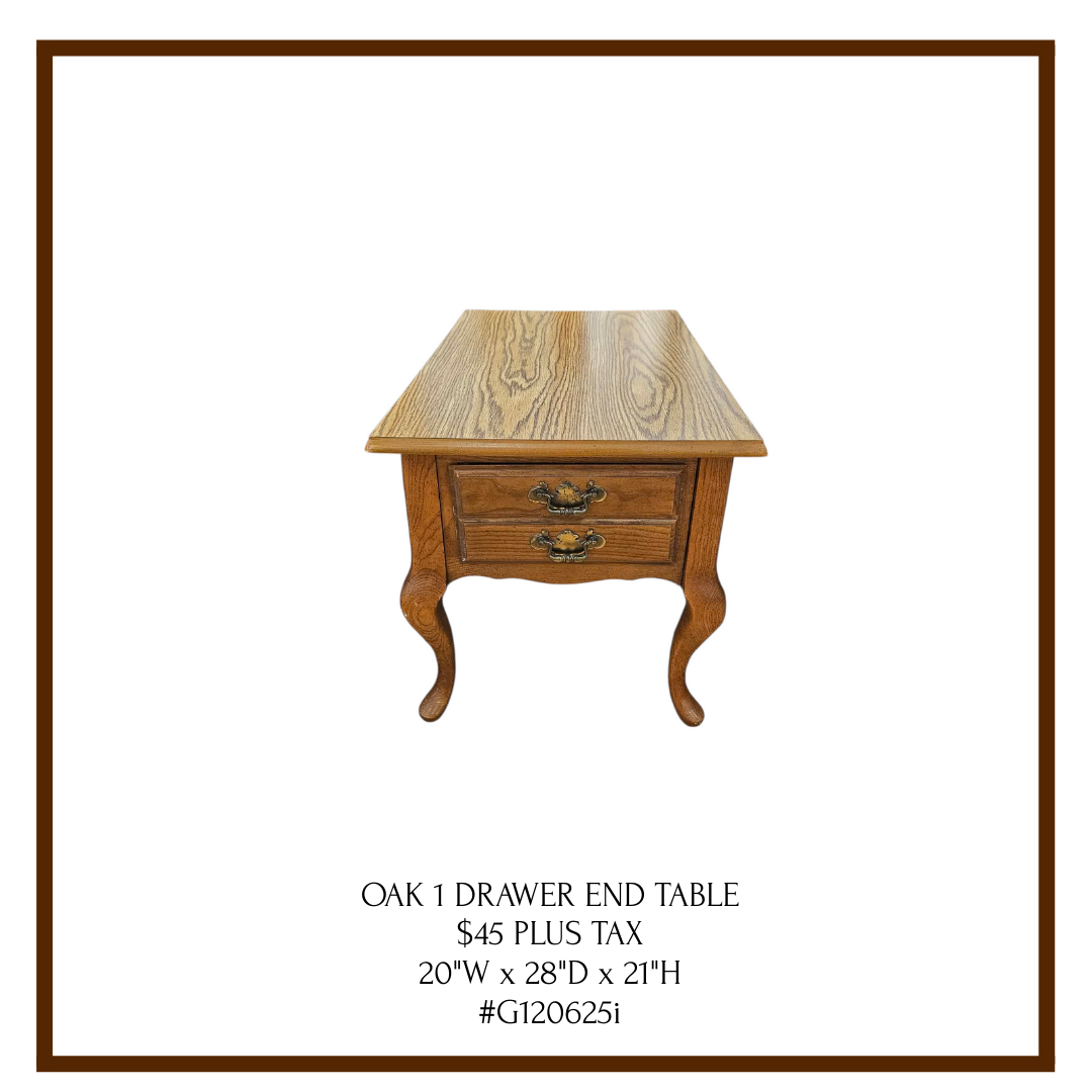 A wooden oak end table with two drawers and ornate handles, standing on curved legs.