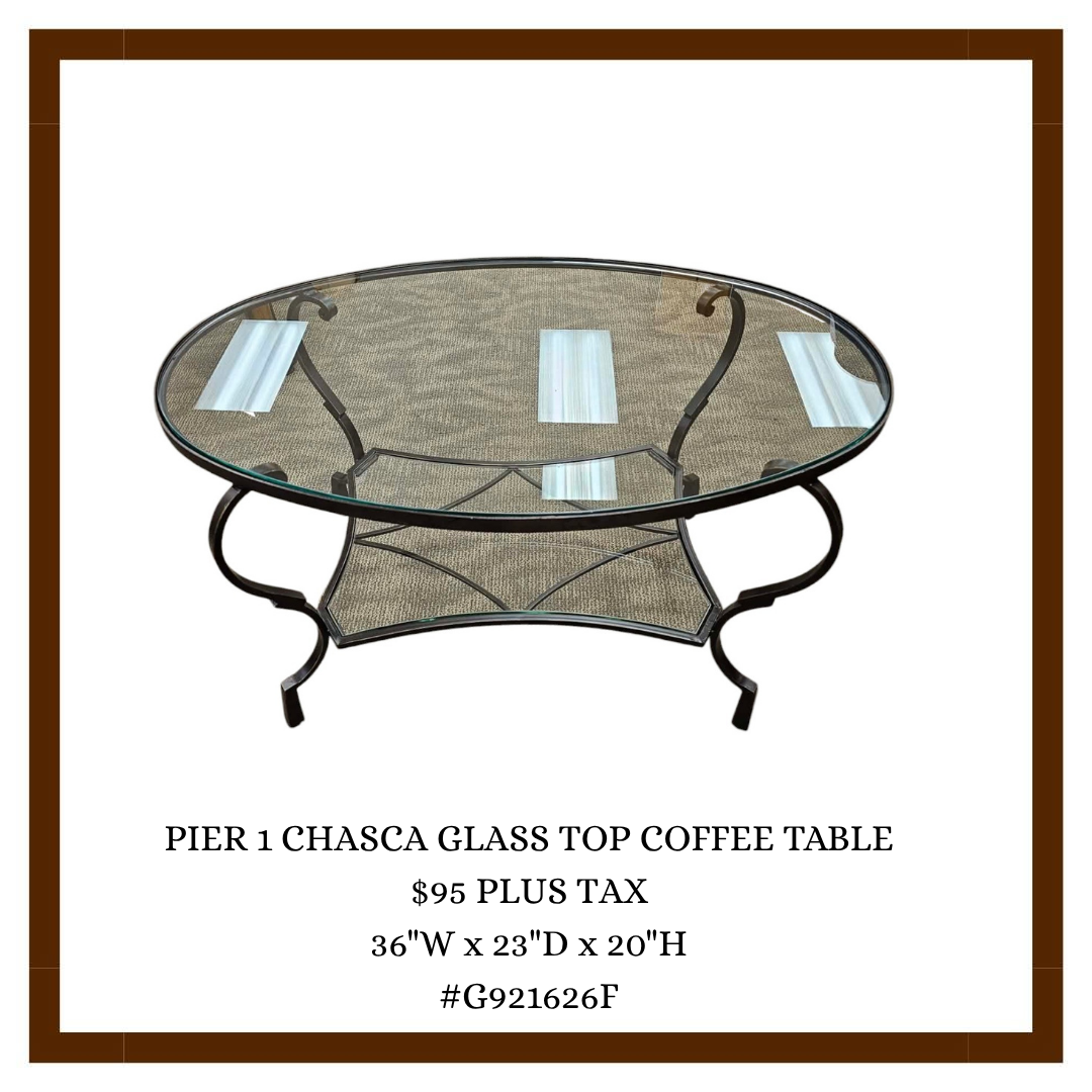 A round coffee table with a glass top, black metal frame, and beige woven shelf underneath, displayed on a white background with a brown border. The text underneath provides details about the table's name, price, dimensions, and item number.