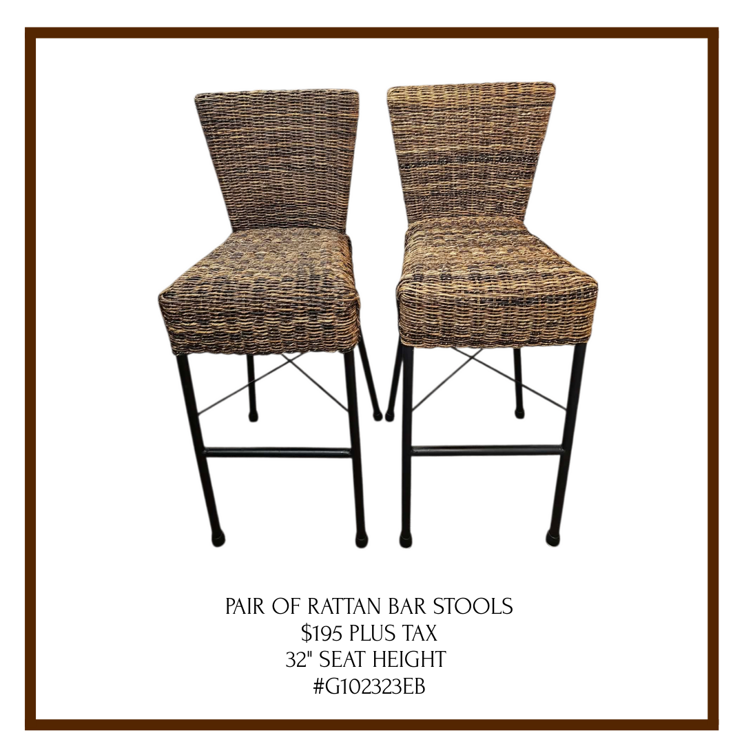 A pair of rattan bar stools with black metal legs, priced at $195 plus tax, with a 32-inch seat height.