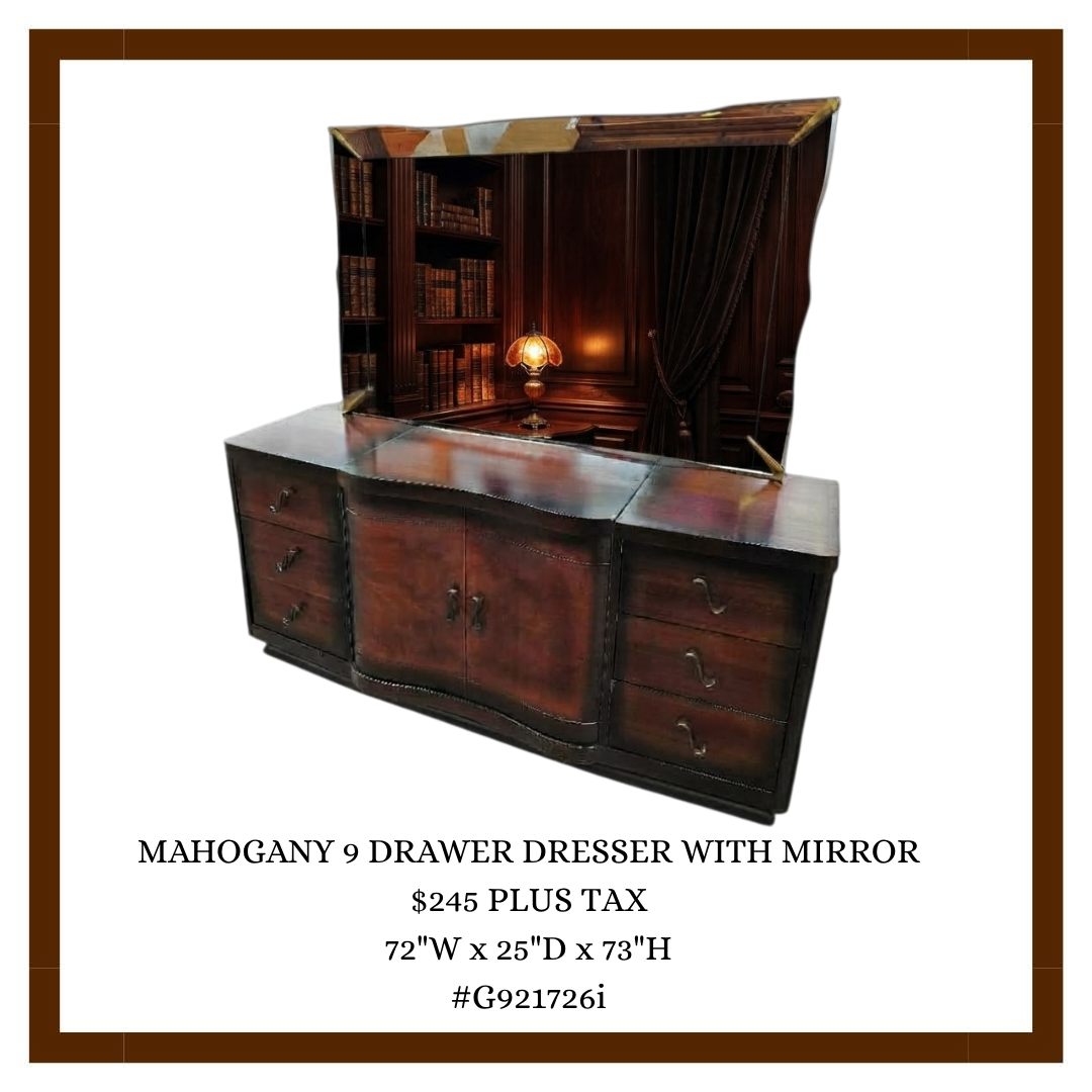 A mahogany 9-drawer dresser with a mirror, showing a reflection of a cozy room with a bookshelf, wooden paneling, a table lamp with a stained glass shade, and dark curtains.