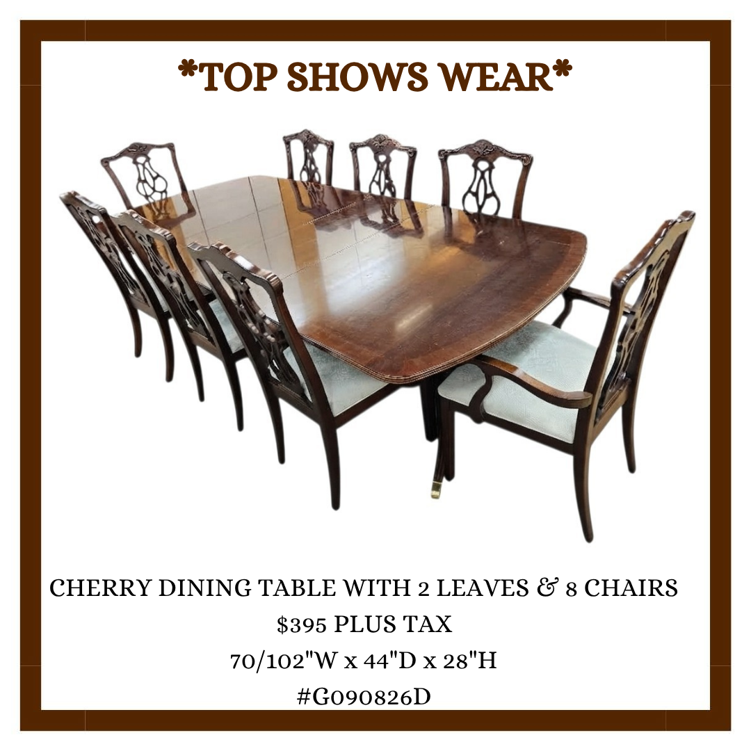A photo of a cherry dining table with eight chairs, six of which have upholstered seats. The table and chairs have a polished wooden finish. The photo is used for a furniture advertisement.
