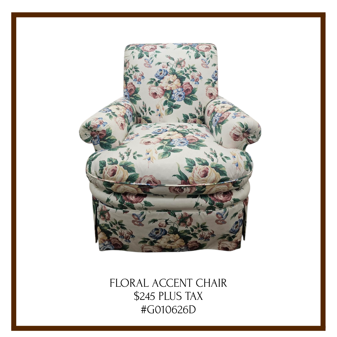 A floral accent chair with a colorful flower pattern, rounded armrests, and a cushioned seat, appearing vintage-style.