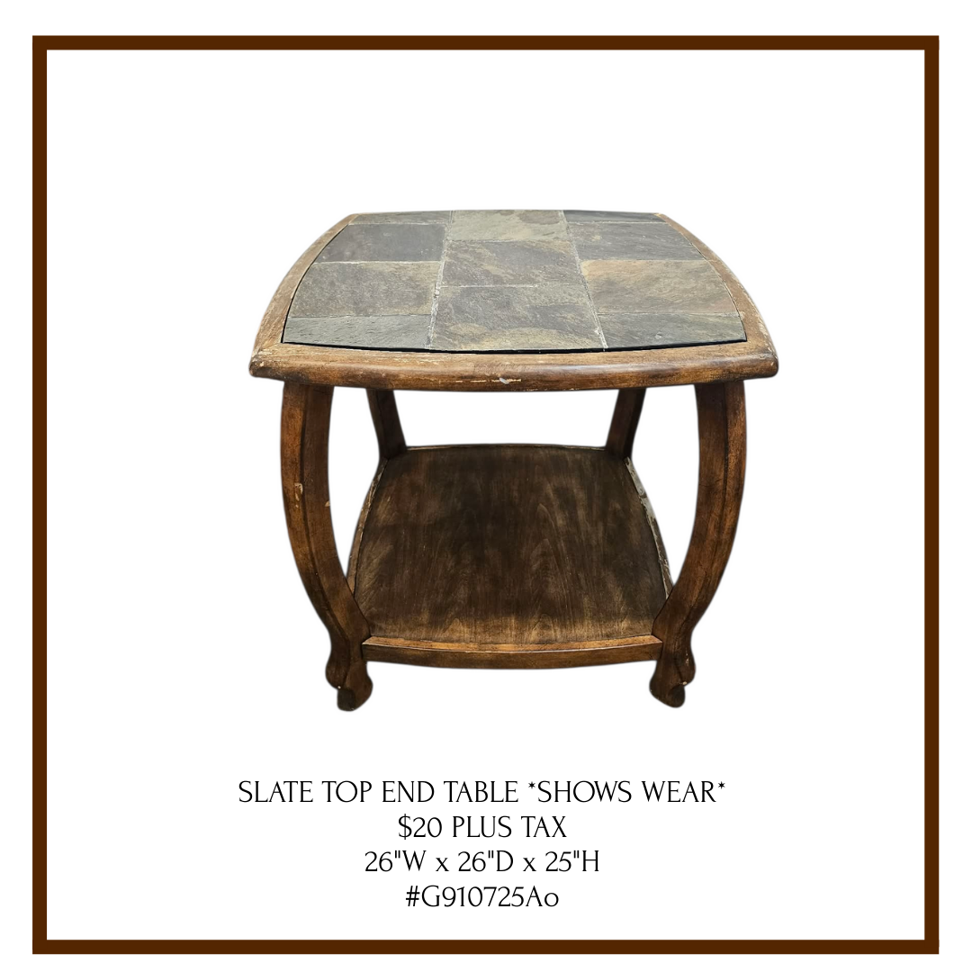 A vintage wooden end table with a slate tile top and a lower shelf, showing signs of wear.