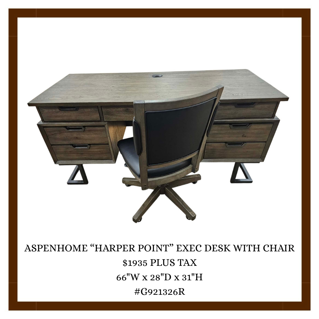 A wooden executive desk with six drawers and a black leather swivel chair.