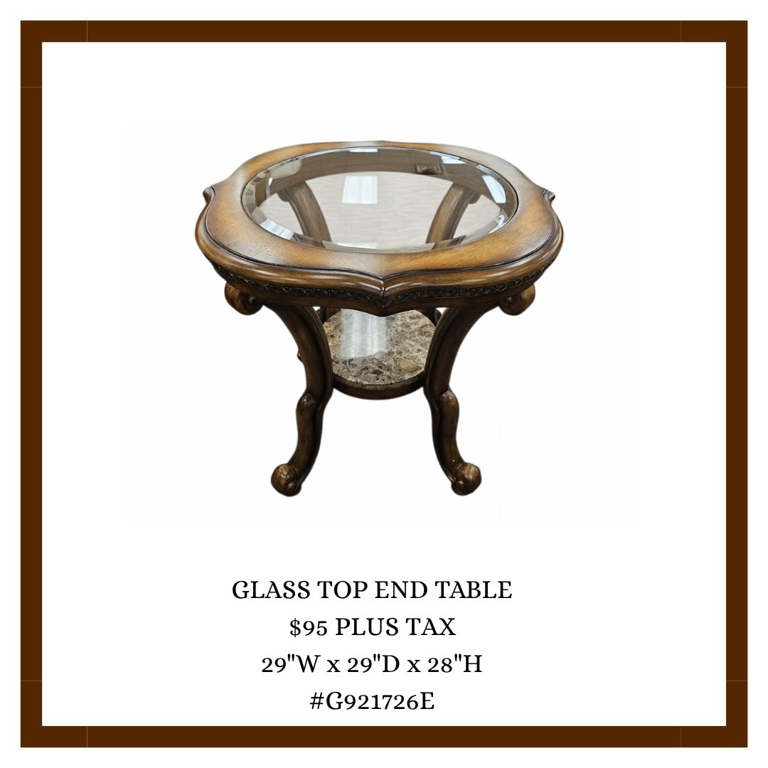 A wooden end table with a glass top and ornate curved legs, featuring a marble shelf underneath.