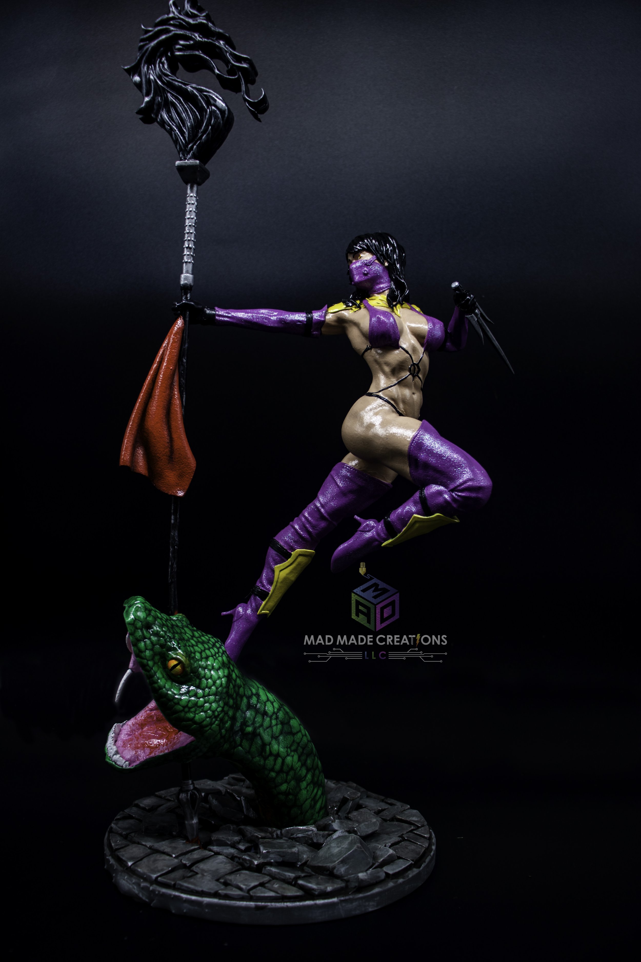 3D printed Mileena fan art statue from Mortal Kombat, hand-painted in purple ninja outfit with sais and red flag, standing on sculpted serpent and stone base, created by MAD Made Creations LLC