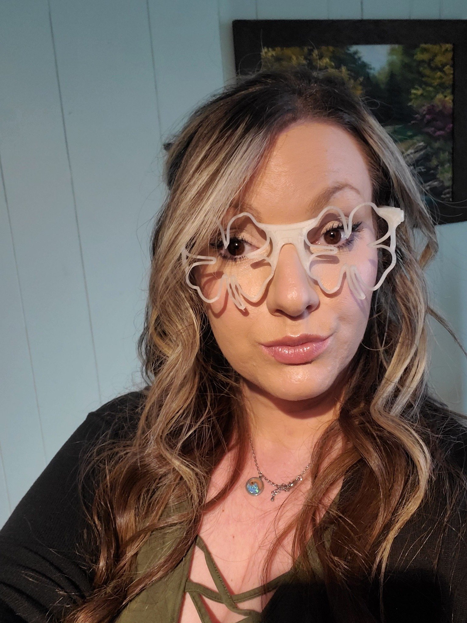 Woman wearing shamrock-shaped 3D printed St. Patrick’s Day glasses made from glow-in-the-dark material by MAD Made Creations LLC, indoors in daylight