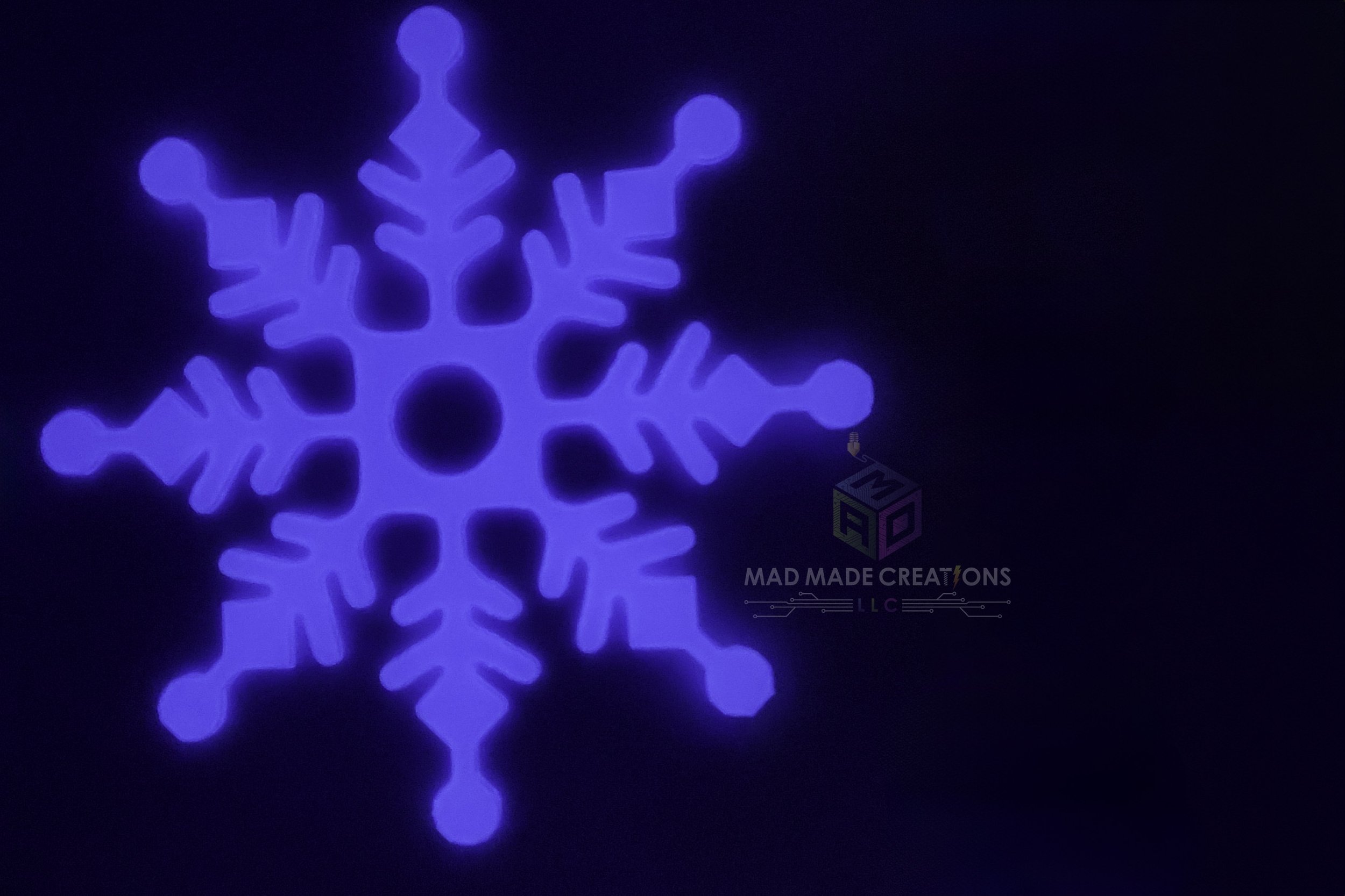 Close-up of one glowing 12-inch blue snowflake decoration from MAD Made Creations’ 3D printed hangable glow-in-the-dark snowflake 4-pack
