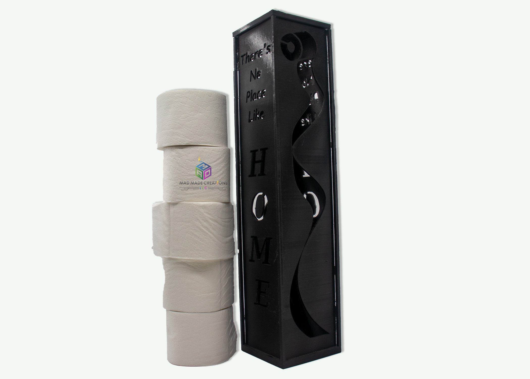 Vertical black 3D printed toilet paper holder with cutout text 'There's No Place Like HOME' beside stacked toilet paper rolls – decorative bathroom storage solution by MAD Made Creations