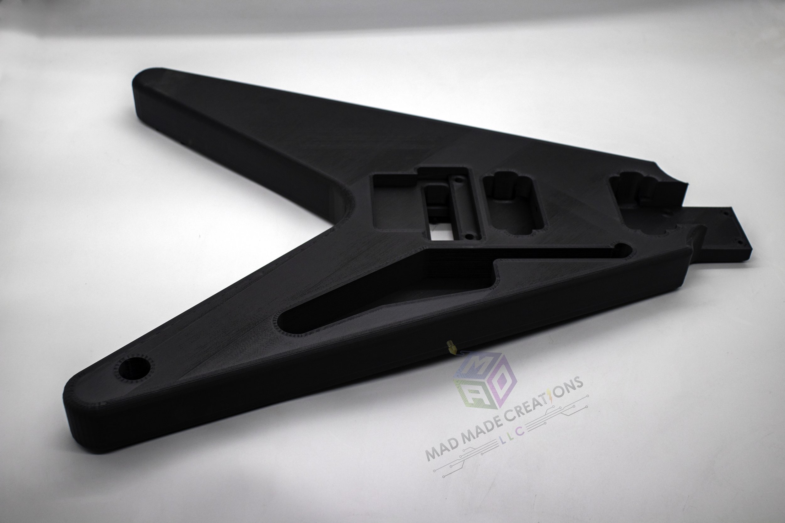 Angled side view of custom 1983 Flying V style guitar body, 3D printed in matte black with Floyd Rose tremolo cavity and HH pickup routing, unpainted and designed by MAD Made Creations LLC