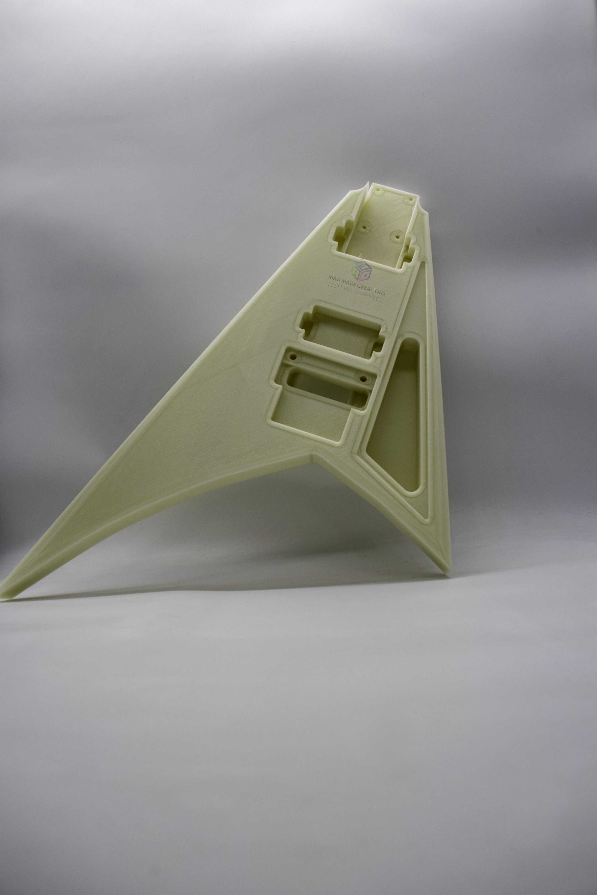 Standing front view of a custom one-piece glow-in-the-dark 3D-printed RR3 Randy Rhoads V-style guitar body, routed for dual humbuckers and Floyd Rose tremolo