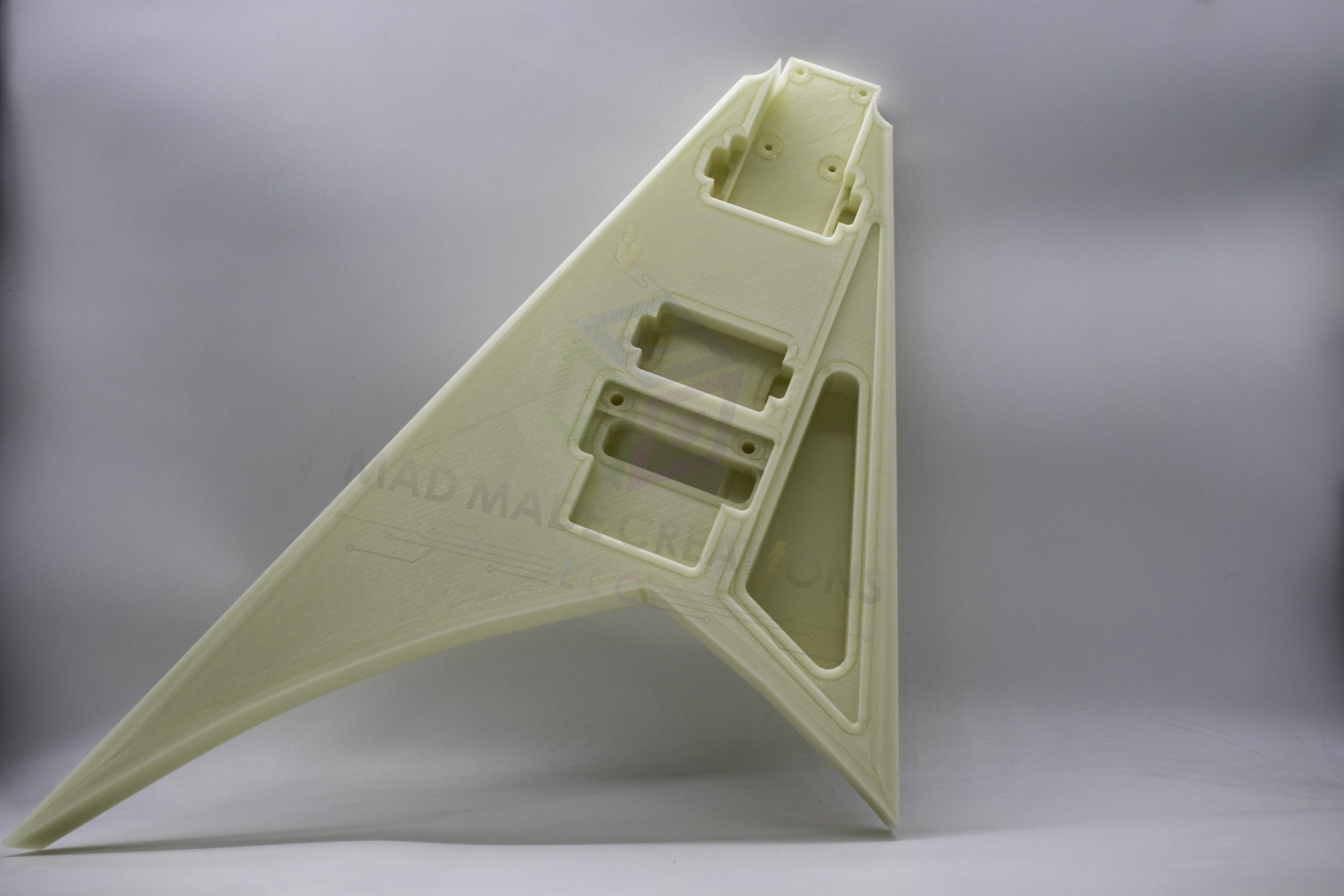 Close-up standing front view of a custom one-piece 3D-printed RR3 Randy Rhoads V-style guitar body in light, routed for HH pickups and Floyd Rose