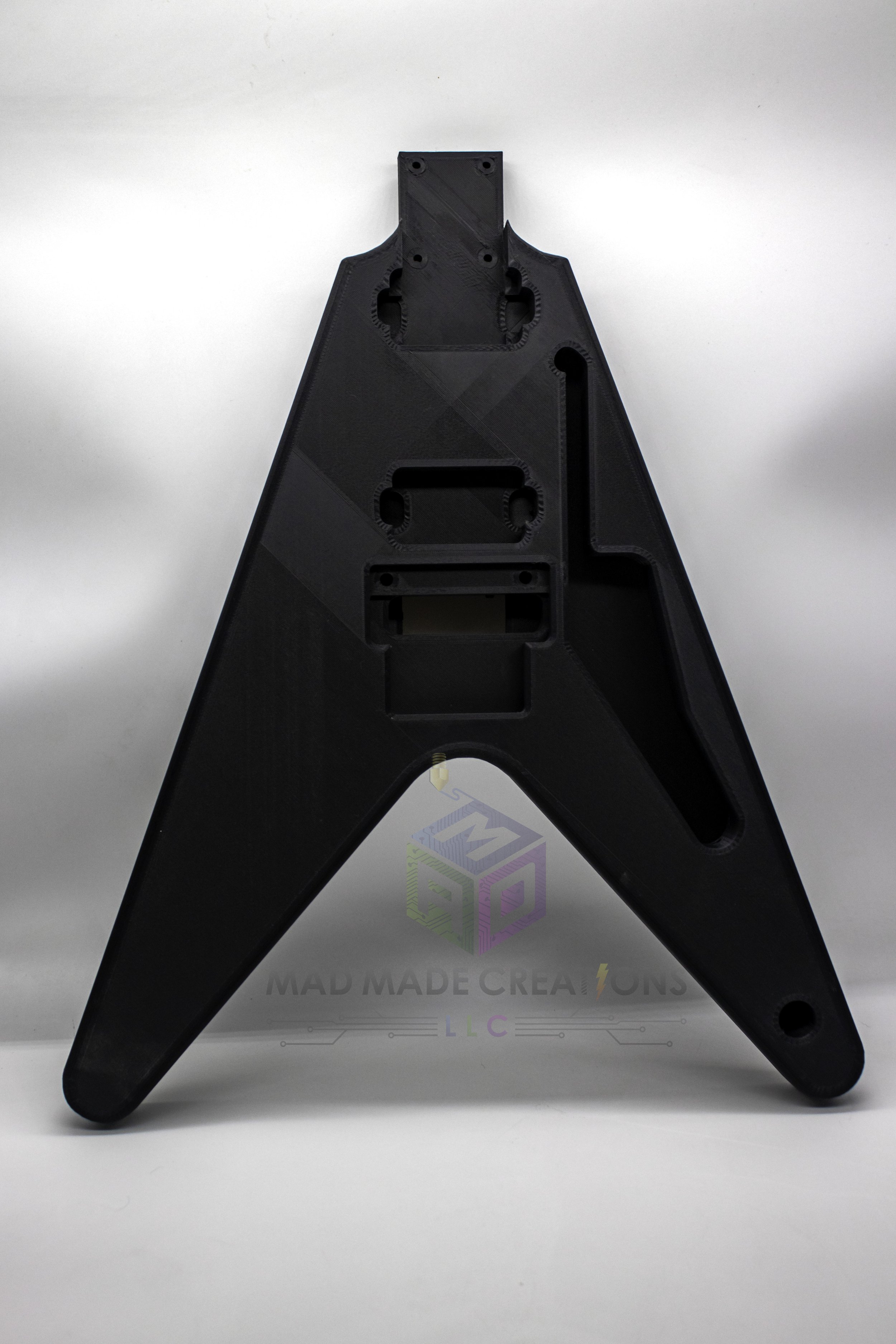 Close-up front view of 3D printed 1983 Flying V style guitar body in matte black, featuring Floyd Rose compatibility and HH pickup routing by MAD Made Creations LLC