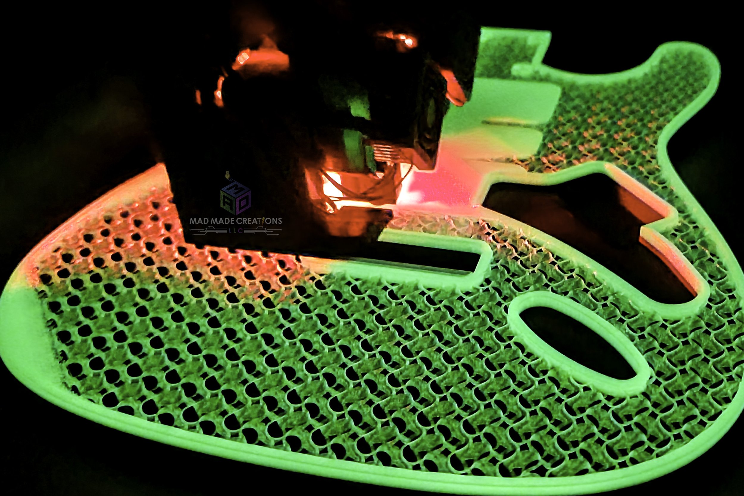 Glow-in-the-dark Strat HSH style guitar body being 3D printed with visible lattice infill, modern tremolo routing, and illuminated by red and green printer lighting from top view