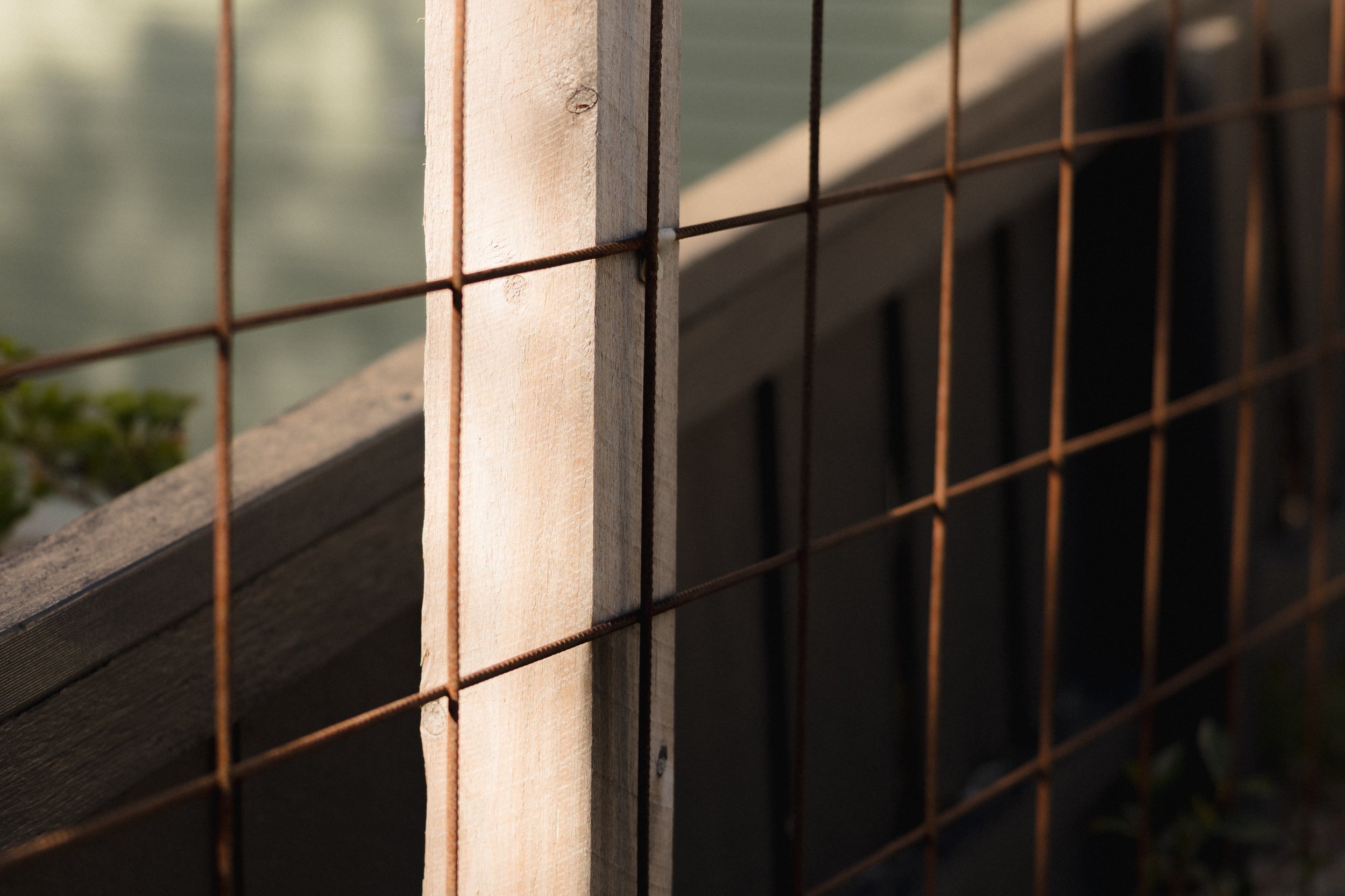 Close-up of a wooden post and rusty wire mesh fence