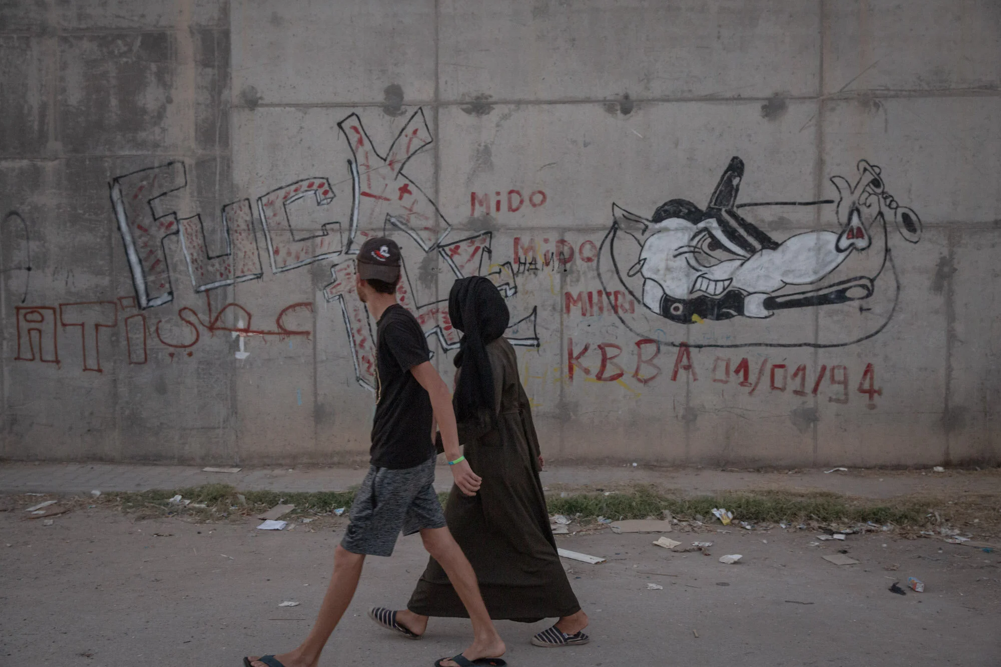 People walking past an anti-police graffiti in El Kabaria, one of the poorer neighborhoods of Tunis