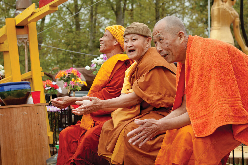 Morganton’s resident monk, Somchit Sengdavone (left), and two visiting monks from Charlotte receive blessings from the laity at the Pi Mai celebration. 