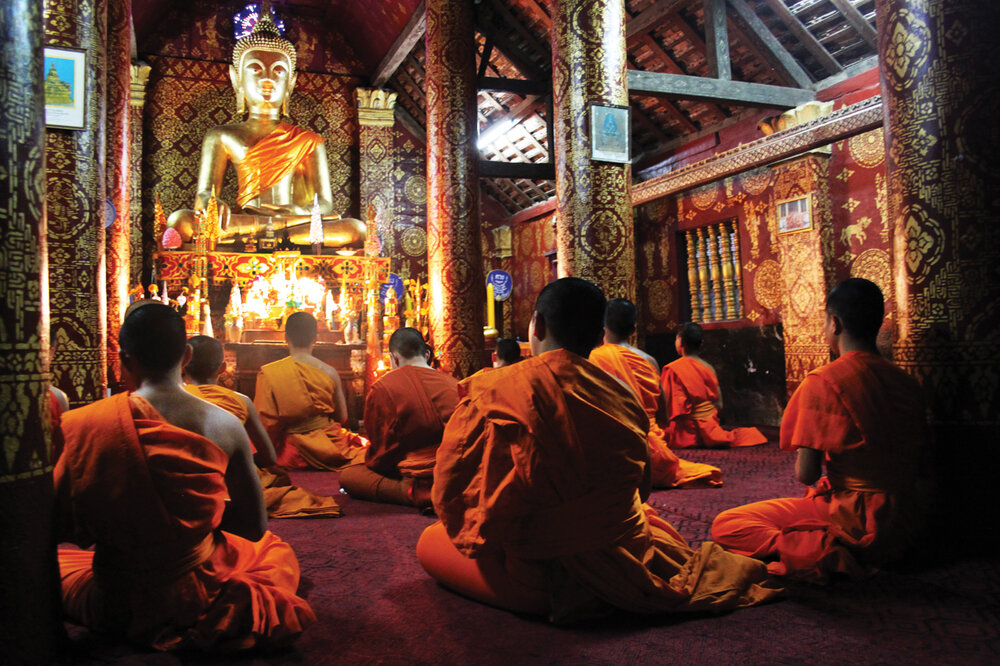 Monks chant during the evening ceremony at a gilded, highly ornamented temple in Laos. This is the magical, sacred space referenced at Wat Lao Sayaphoum. (Luang Prabang, Laos) 