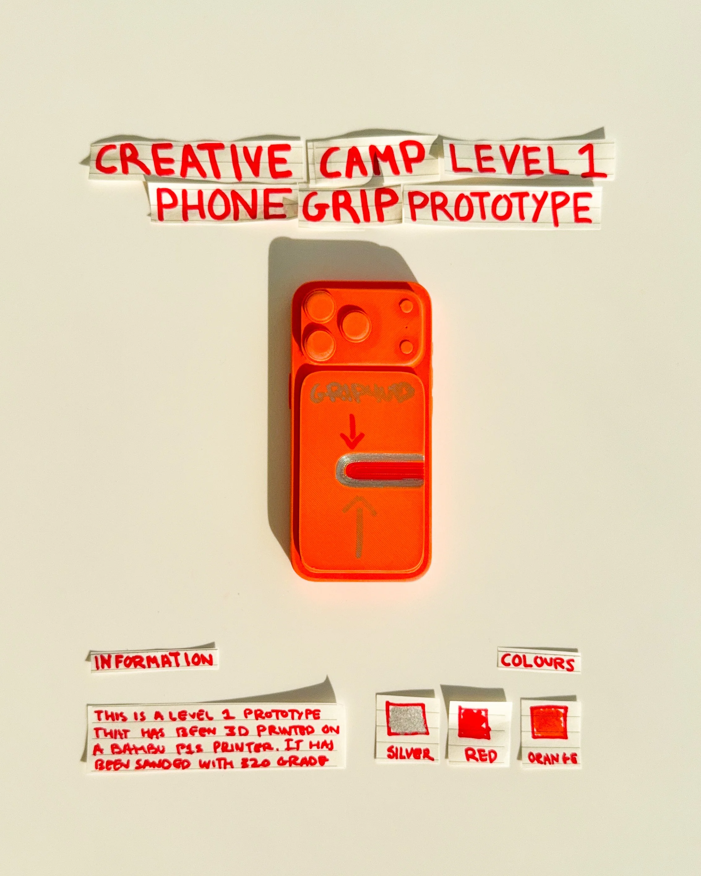 day 30 prototype 28: explore an orange rectangular phone grip with a single horizontal finger opening, silver detailing and handwritten arrows. the design focuses on simplifying the grip mechanism while maintaining a strong visual identity.