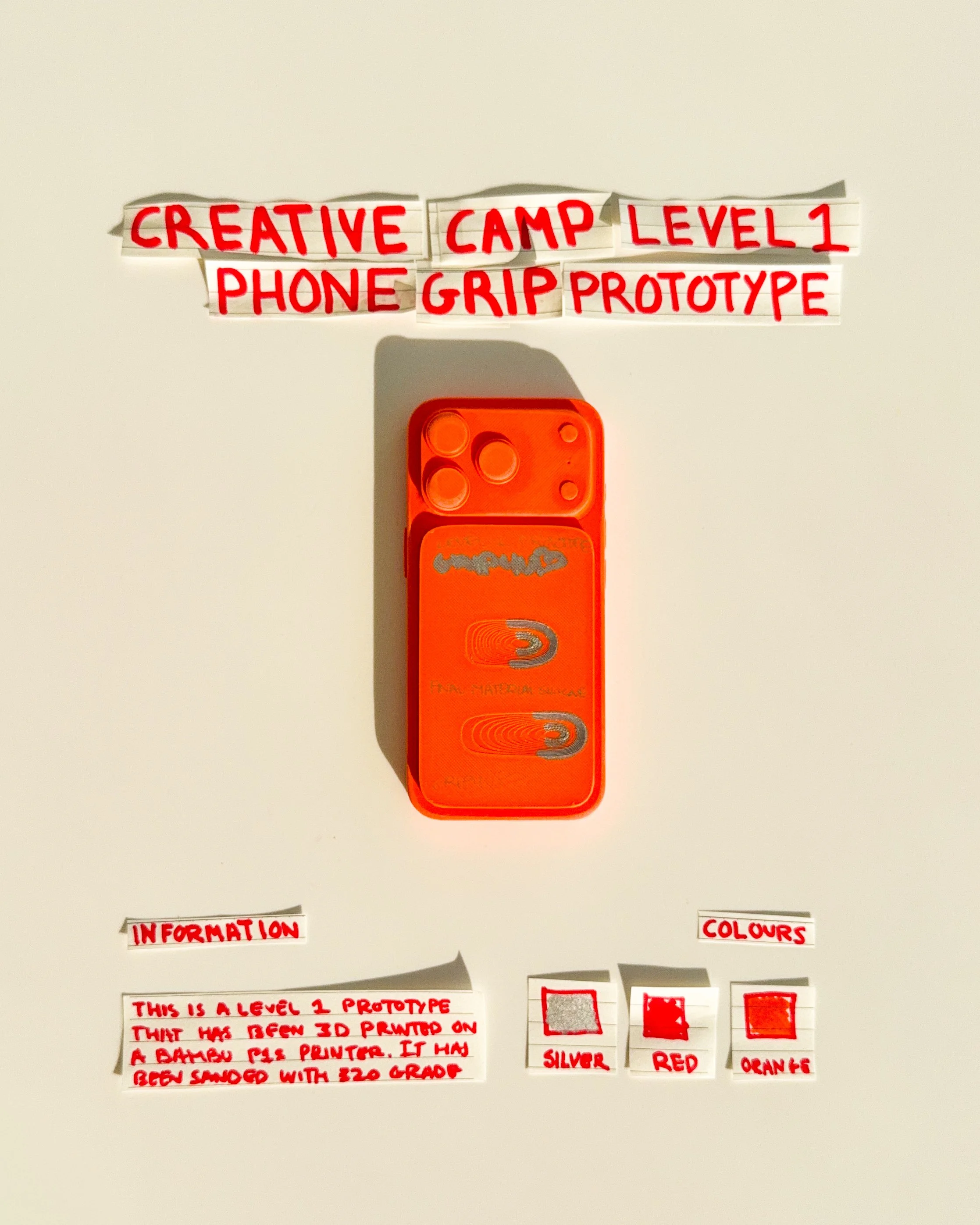 day 29 prototype 27: develop an orange rectangular phone grip featuring two circular finger openings, black outlines and directional graphics. the design explores repeated shapes, contrasting details and a more expressive visual identity.