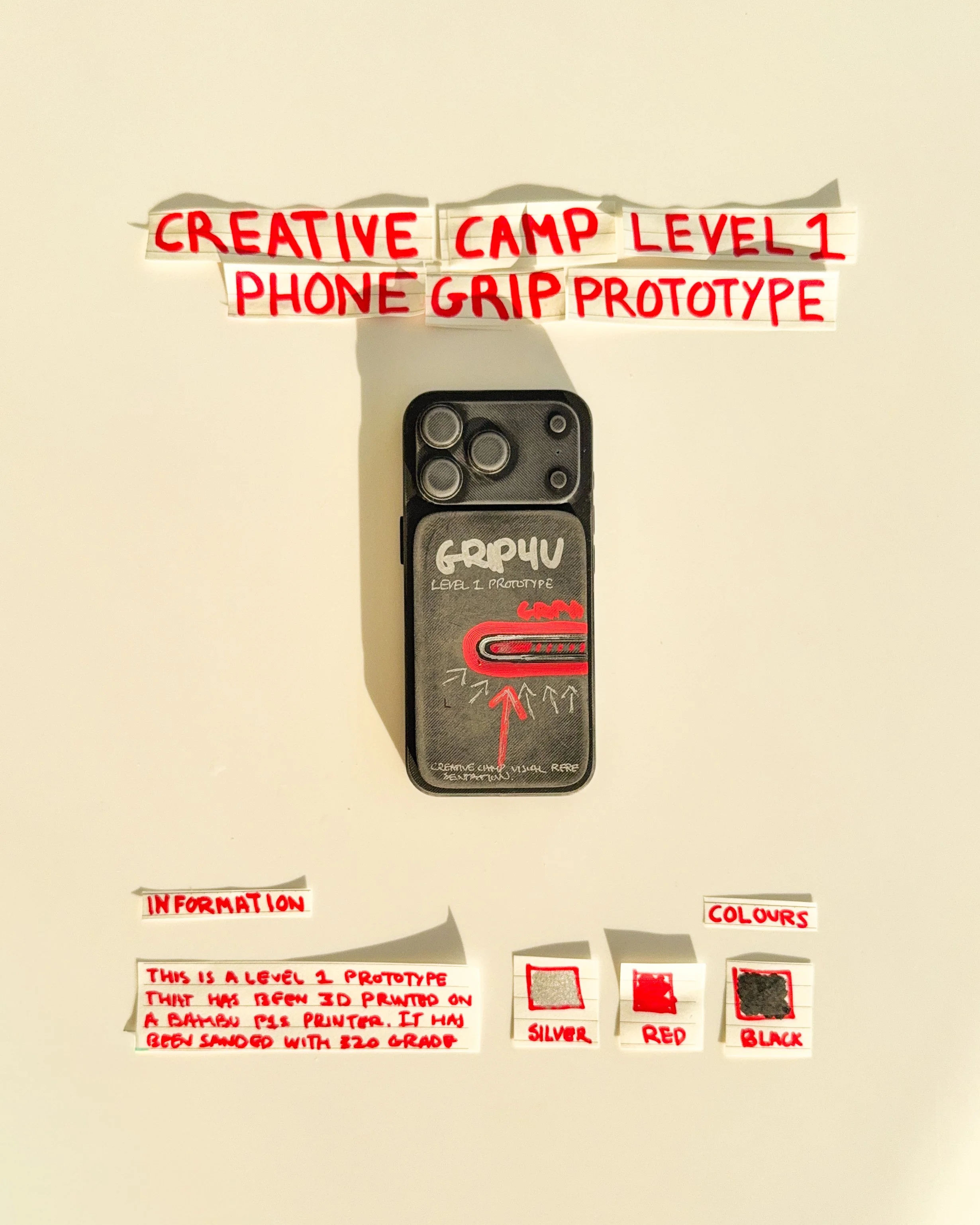 day 12 prototype 10: explore a rectangular phone grip with handwritten graphics, red detailing and a horizontal finger opening. the design combines functional elements with a more expressive visual identity.