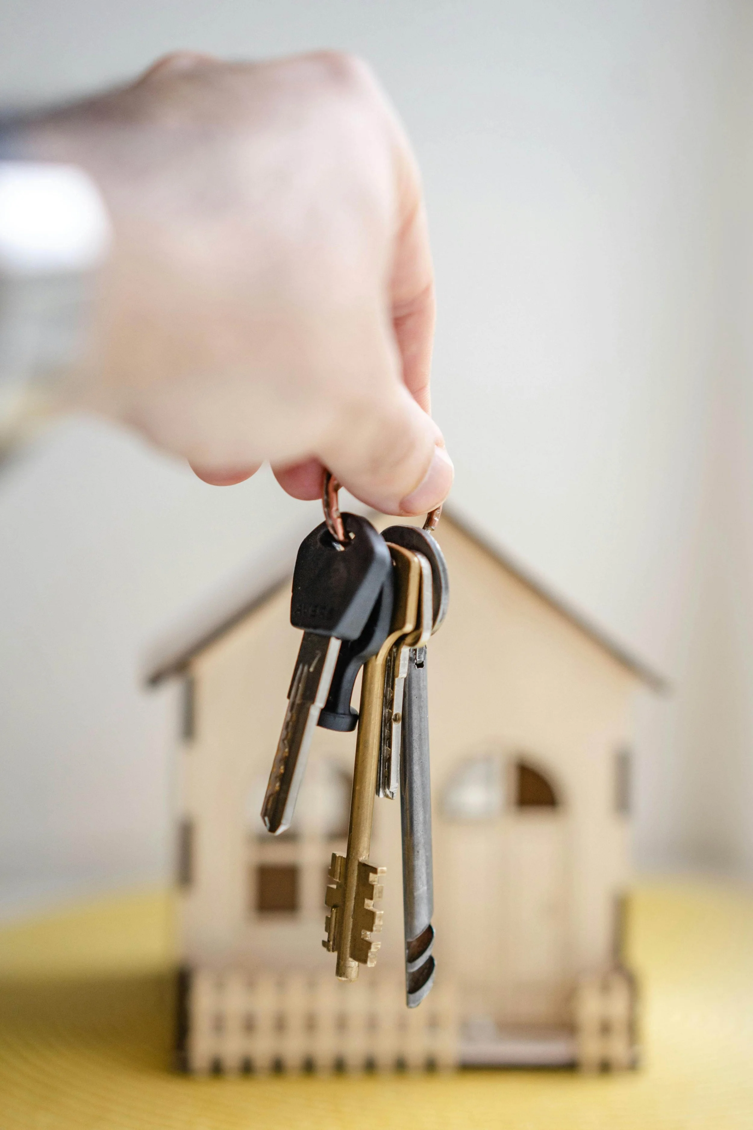 This image is clickable. Hand is holding set of keys in front of a house
