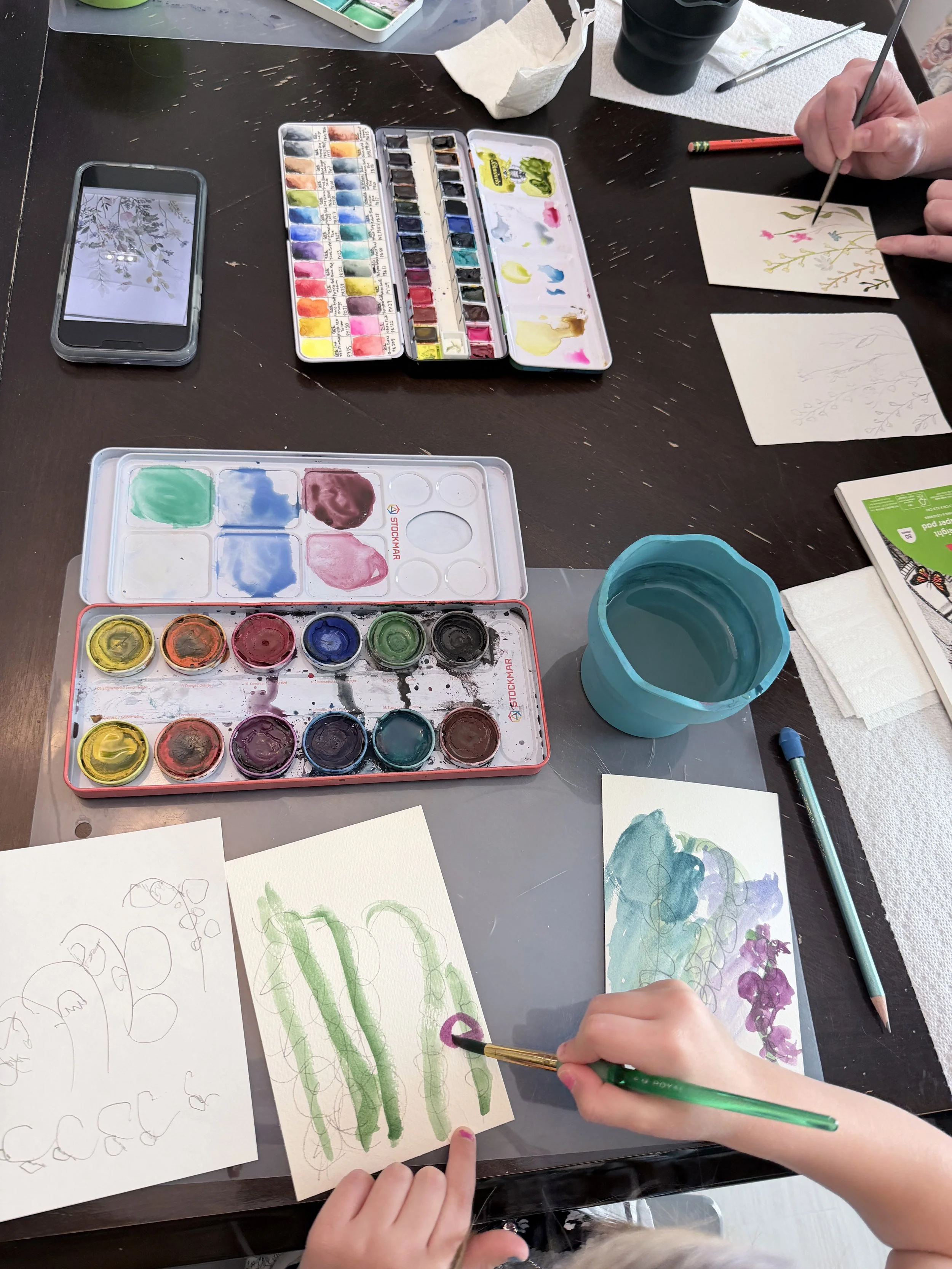 preschooler painting green stems of wildflowers on watercolor paper