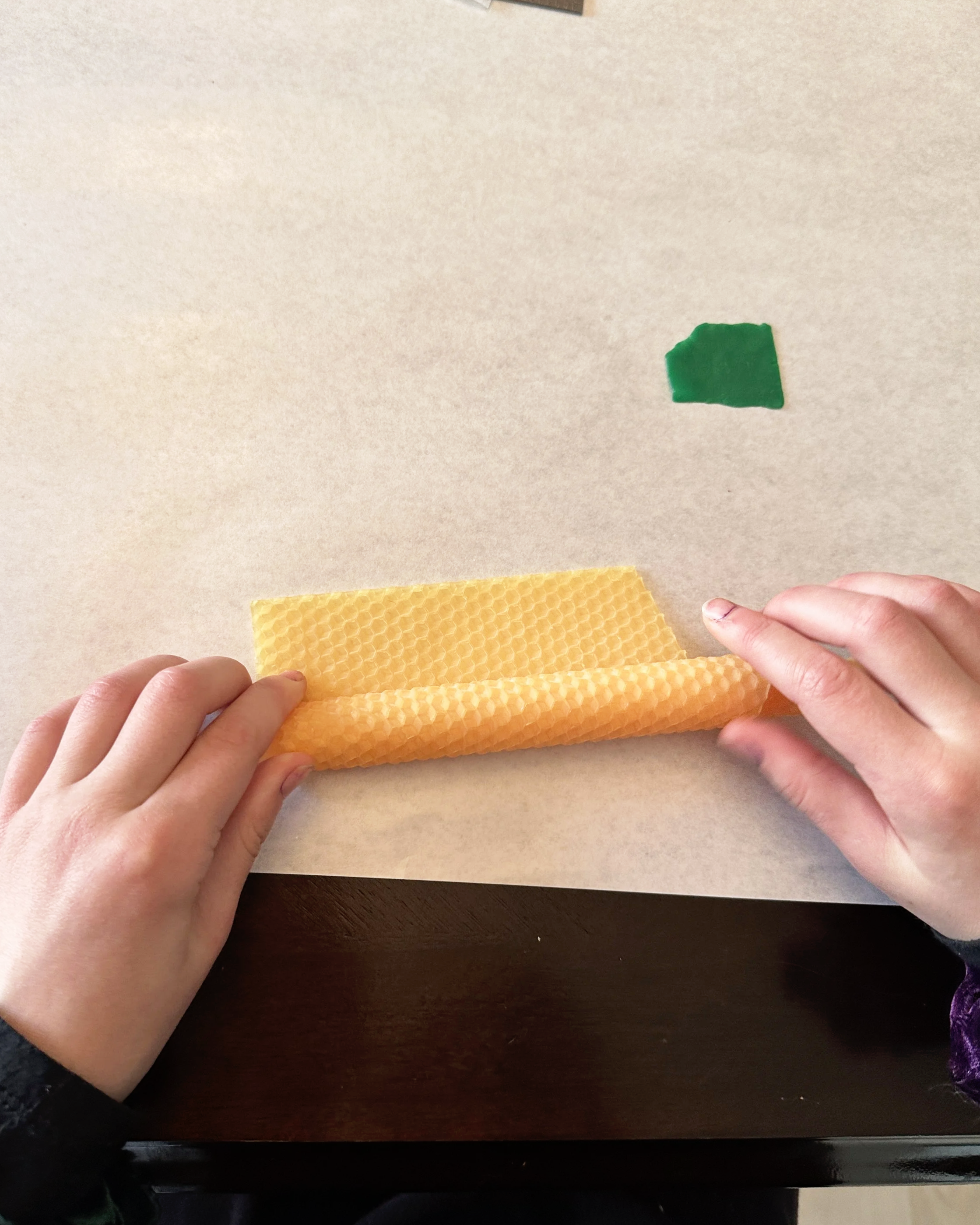 teen rolling a sheet of beeswax to make a homemade candle handicraft