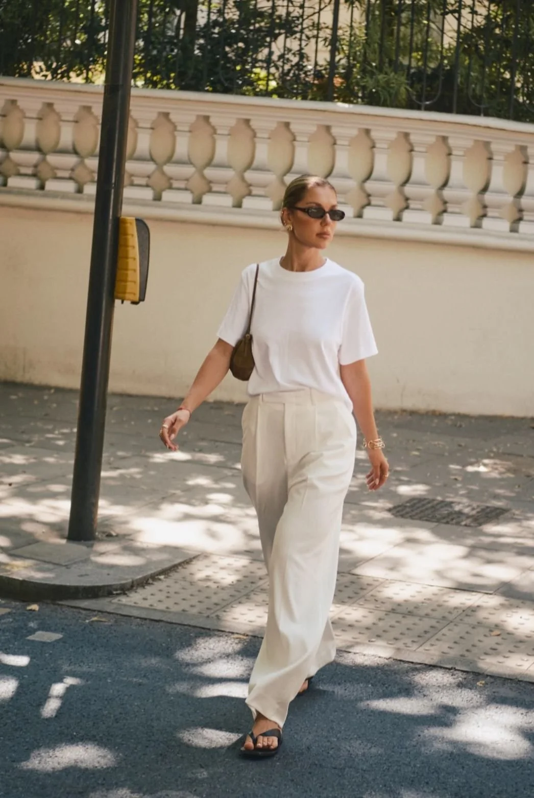 Neutral summer outfit featuring a white cotton T-shirt, linen trousers, and simple leather sandals.