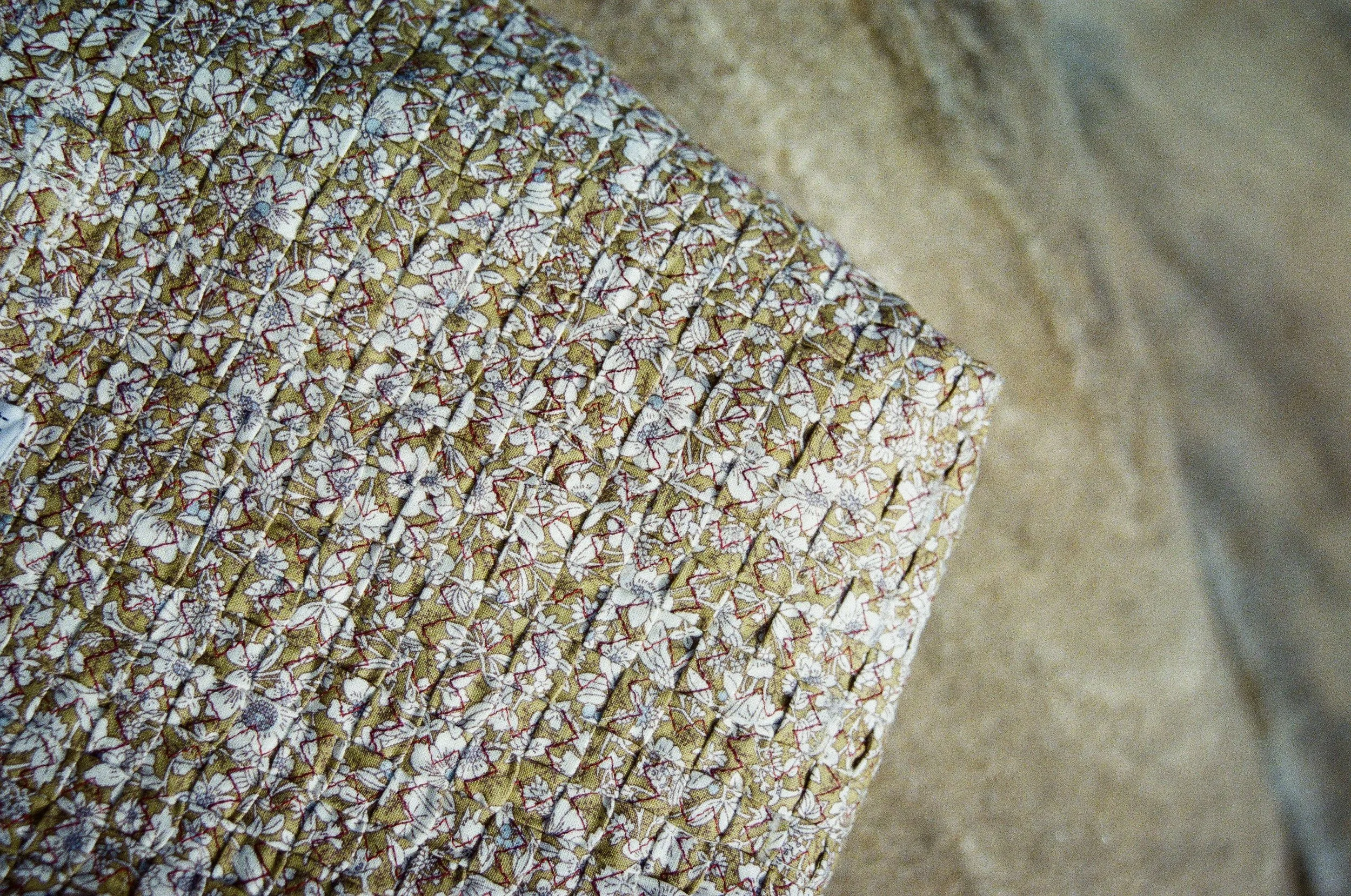 Close-up of a fabric with a floral pattern and parallel stitching.