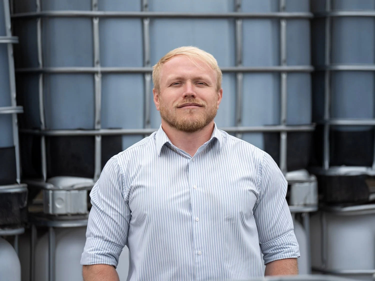 Rich Scott, New Business Sales Manager at Castle Environmental wearing a striped shirt in front of industrial containers