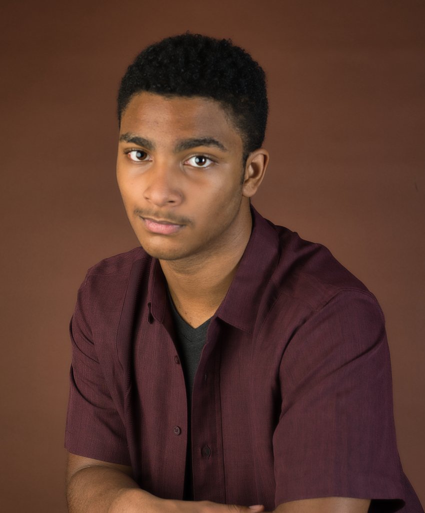 Young man looking directly at the camera with a brown background