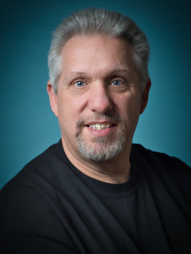 Man smiling into the camera with dark blue background