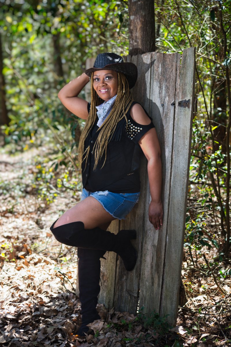 Cowgirl leaning on a fence in the woods