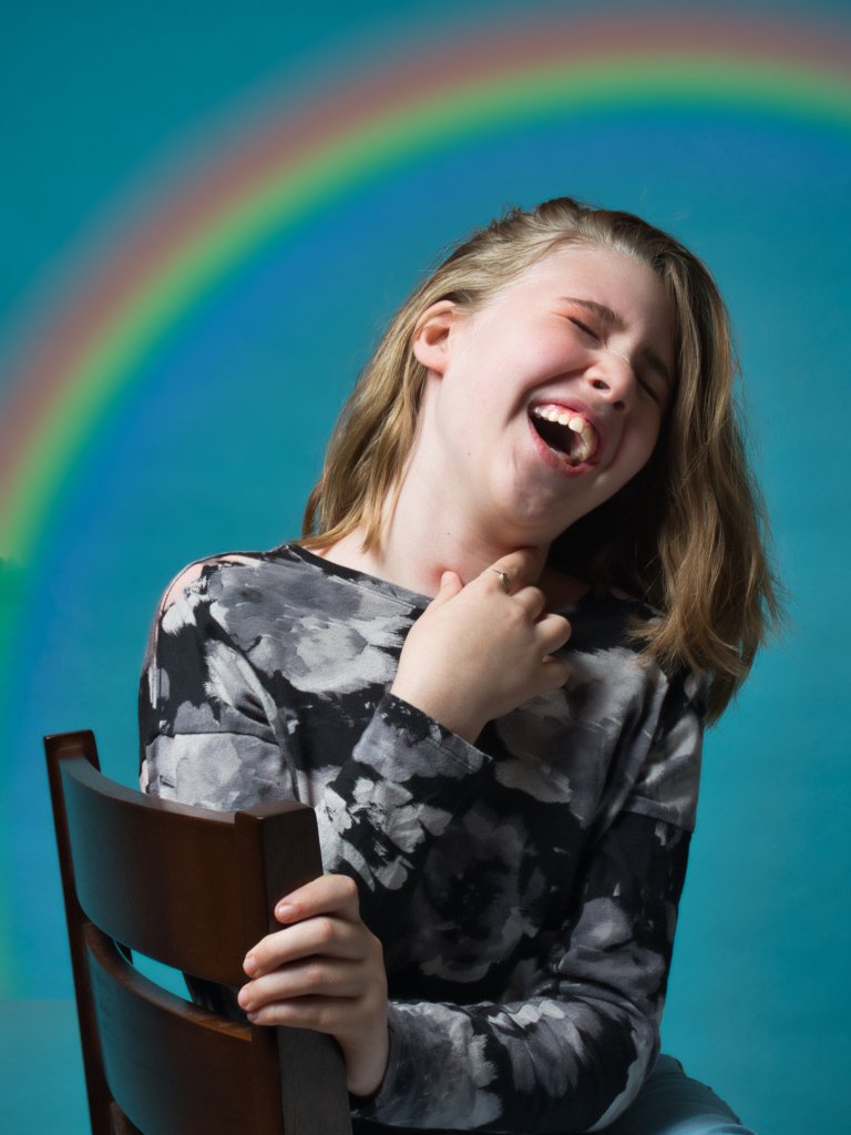 Young girl laughing under a rainbow