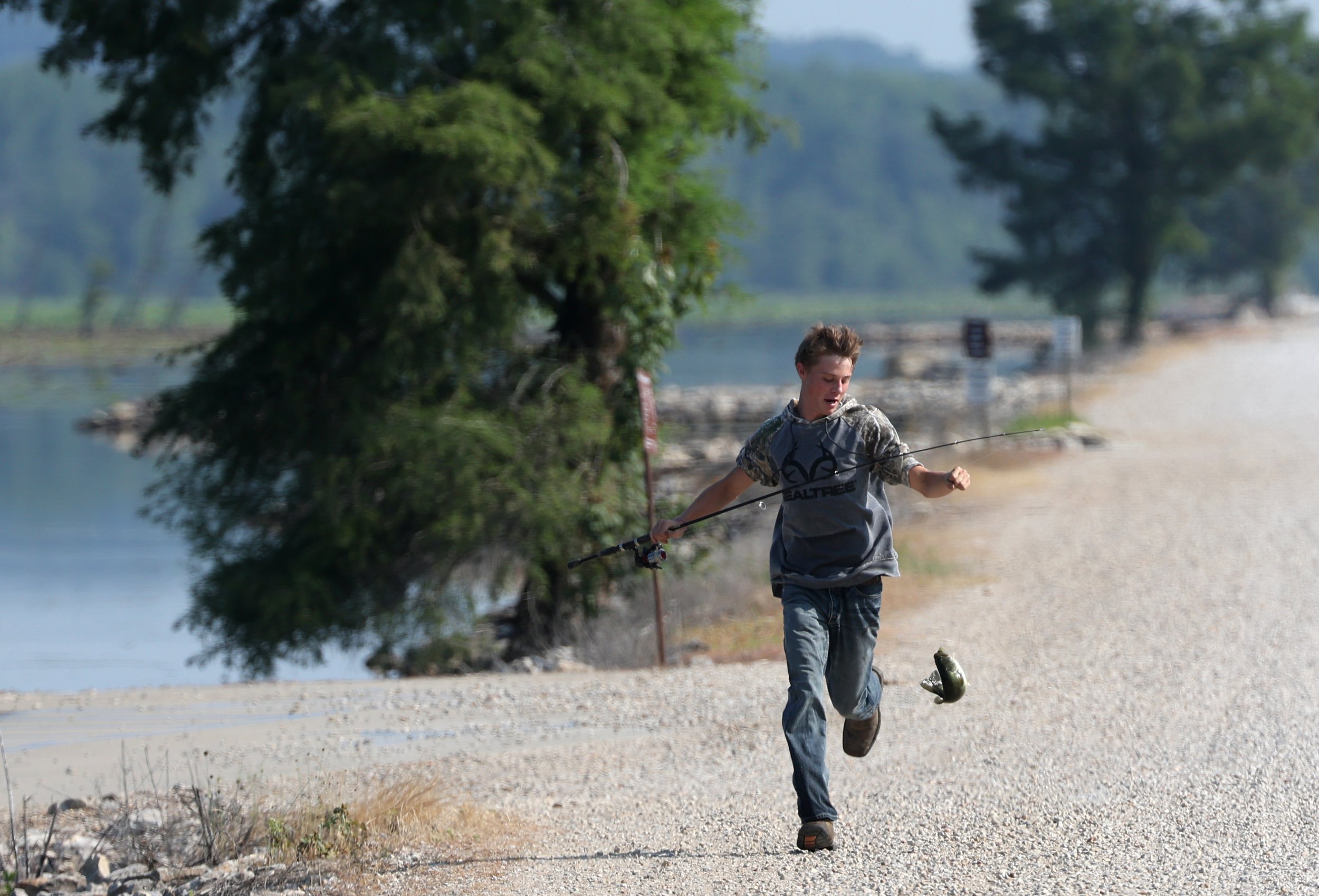  Jeremy Kilburn, 15, runs up the road to his grandfather Tom Kilburn after catching a fish Thursday, June 18, 2023, at Duck Creek Conservation Area in Wayne County in Missouri. The northern snakehead, an invasive fish species, was found for the secon