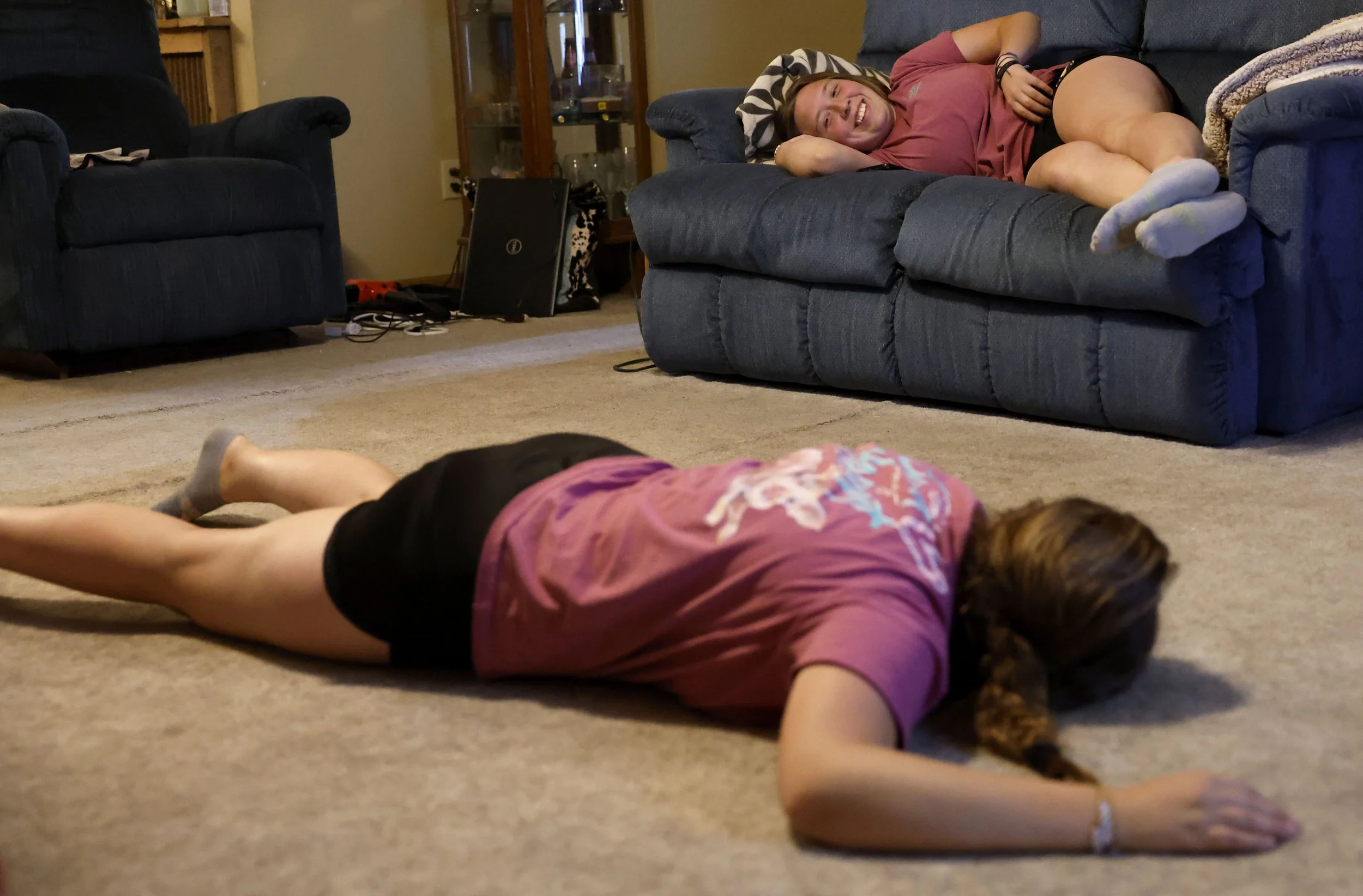  Jordan Shields, bottom, and her twin sister Bailey Shields, top, share a laugh as they relax at the end of their day Thursday, June 13, 2024, at their home in Winfield.  