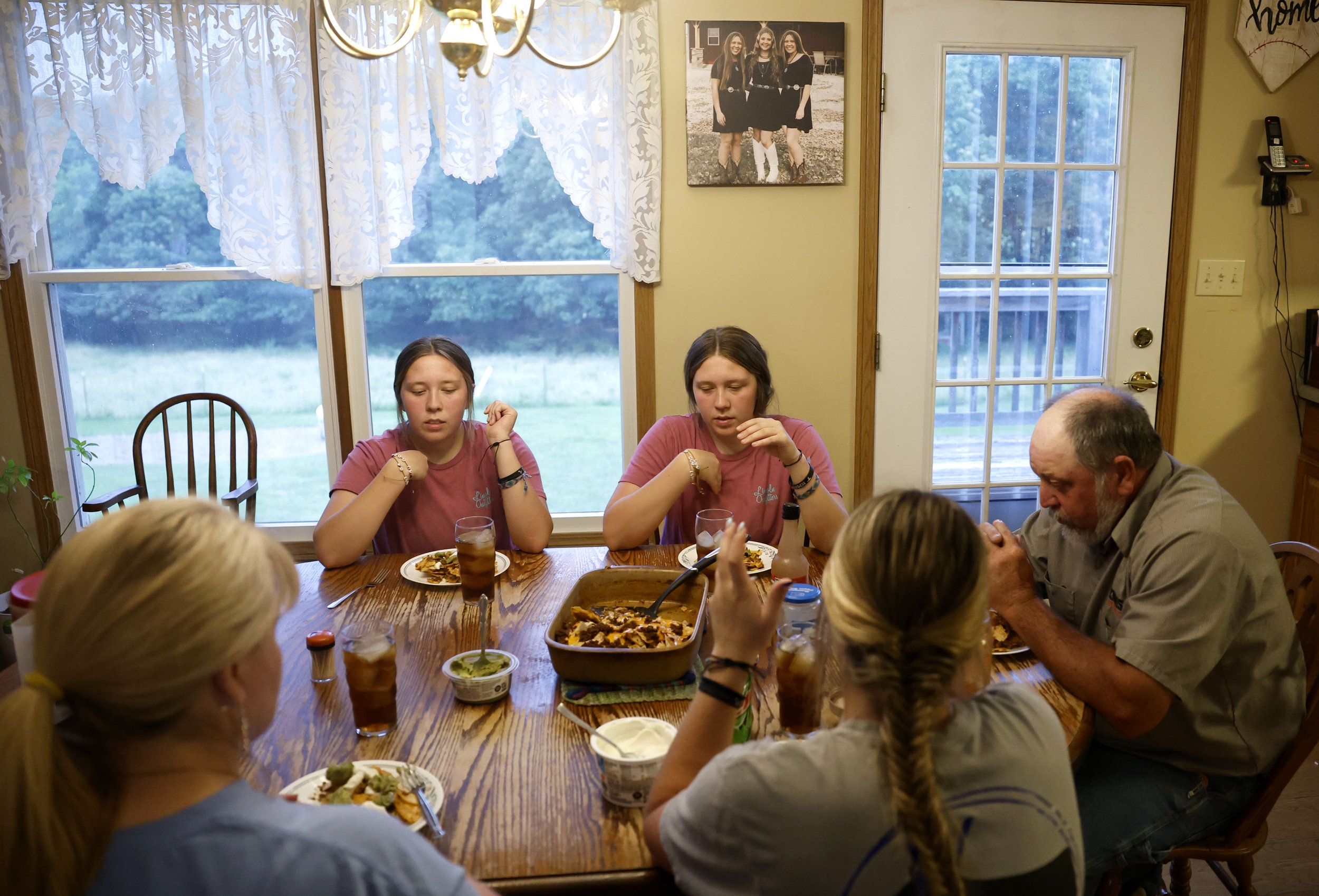  Bailey Shields, left, and her twin sister Jordan Shields, right, pray before they eat dinner with their family, including, from left, mom Melitta Shields, sister Morgan Shields and dad Gary Shields, on Thursday, June 13, 2024, at their home in Winfi