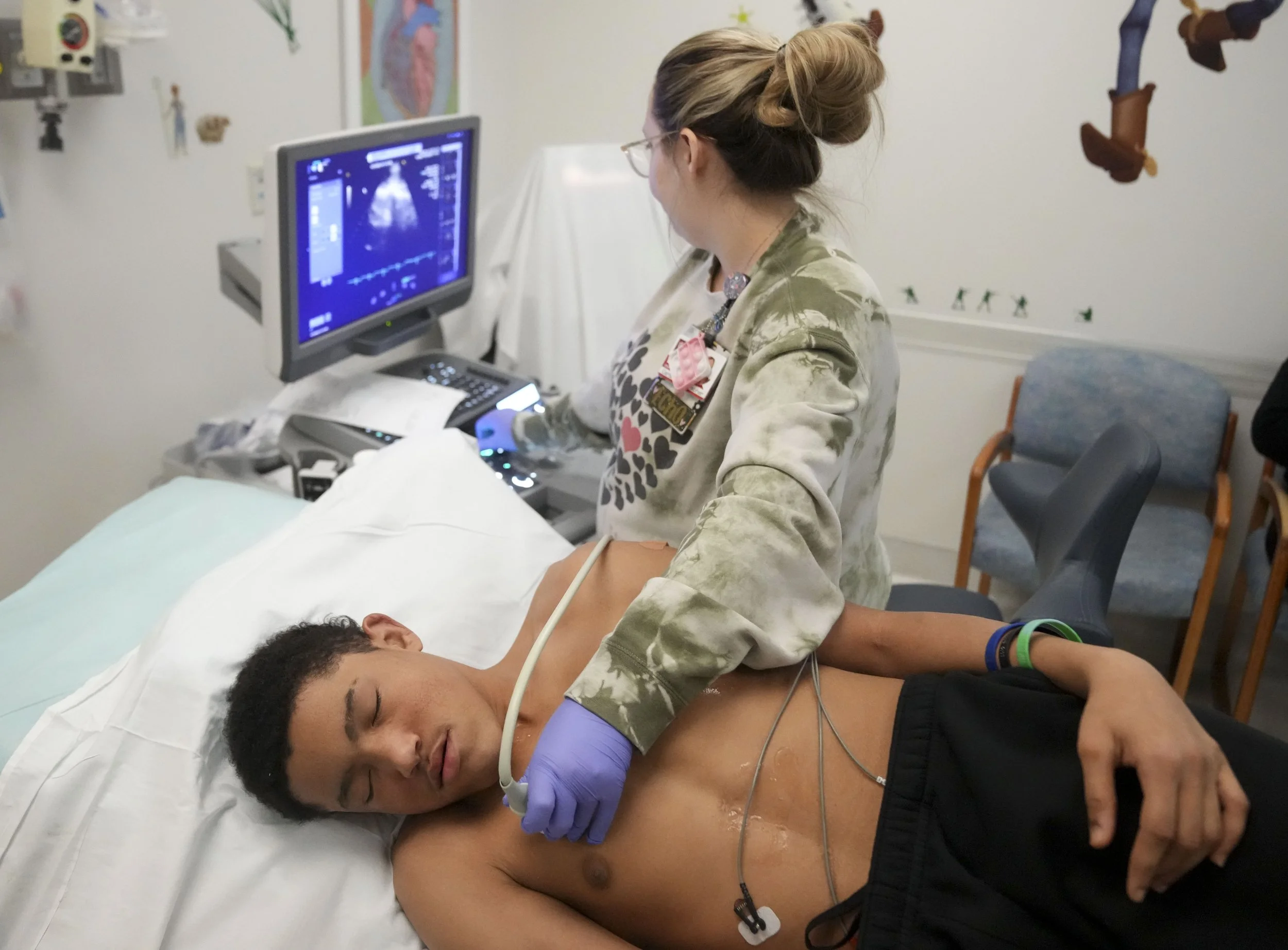  Cardiac sonographer Emily Westfall (back) takes a look at Eli Otero III during a check-up on Tuesday, Dec. 17, 2024, at Riley Hospital for Children in Indianapolis. Otero III has Alagille syndrome and received a liver transplant in 2020 as a result.