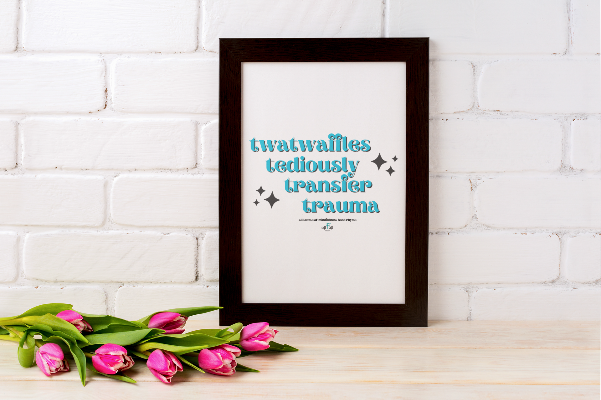 A framed quote on a white brick wall reading 'twatwaffles tediously transfer trauma' with pink tulips on a wooden surface in front.