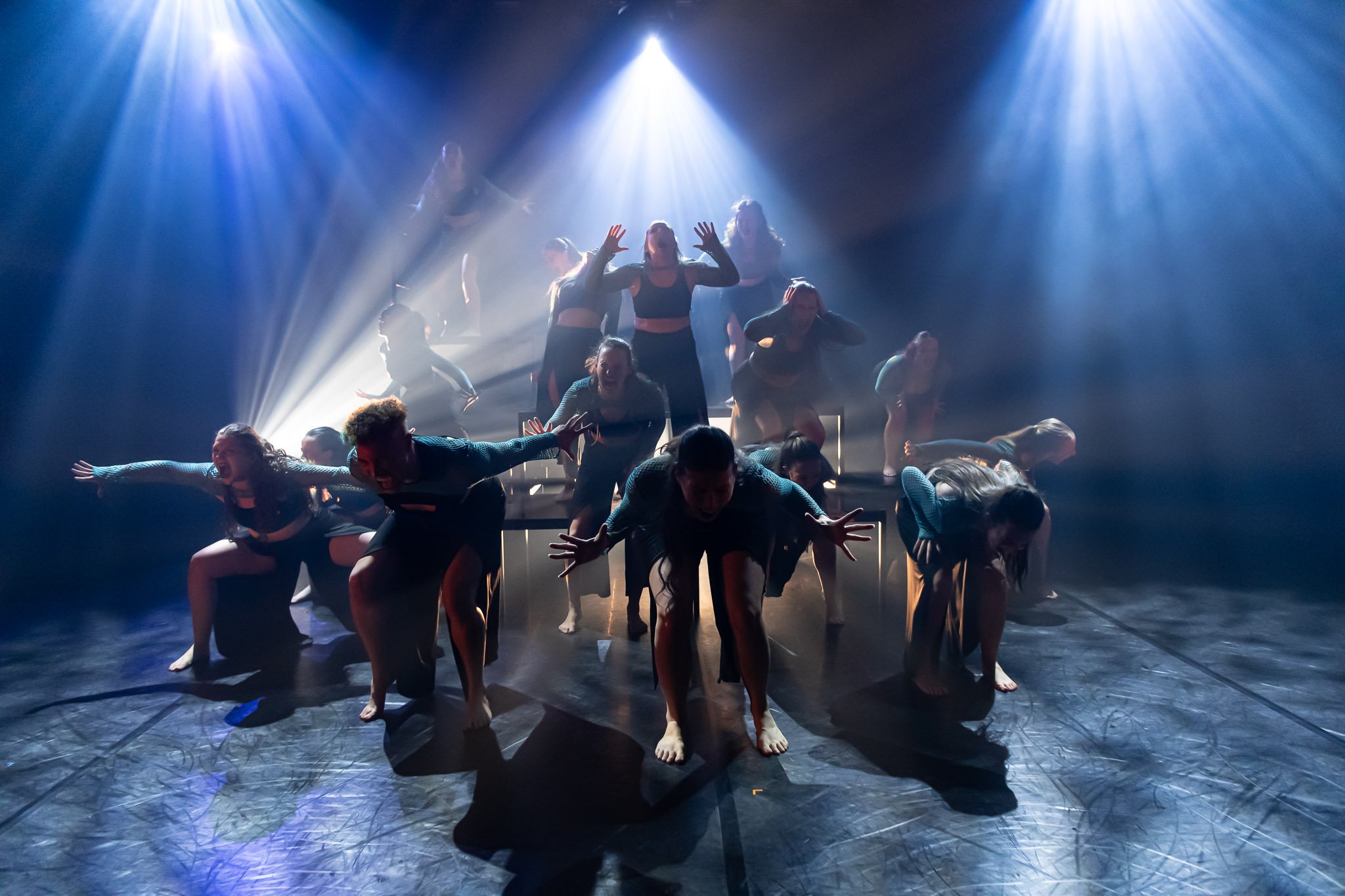 Dance performance with dancers in dynamic poses, blue stage lighting