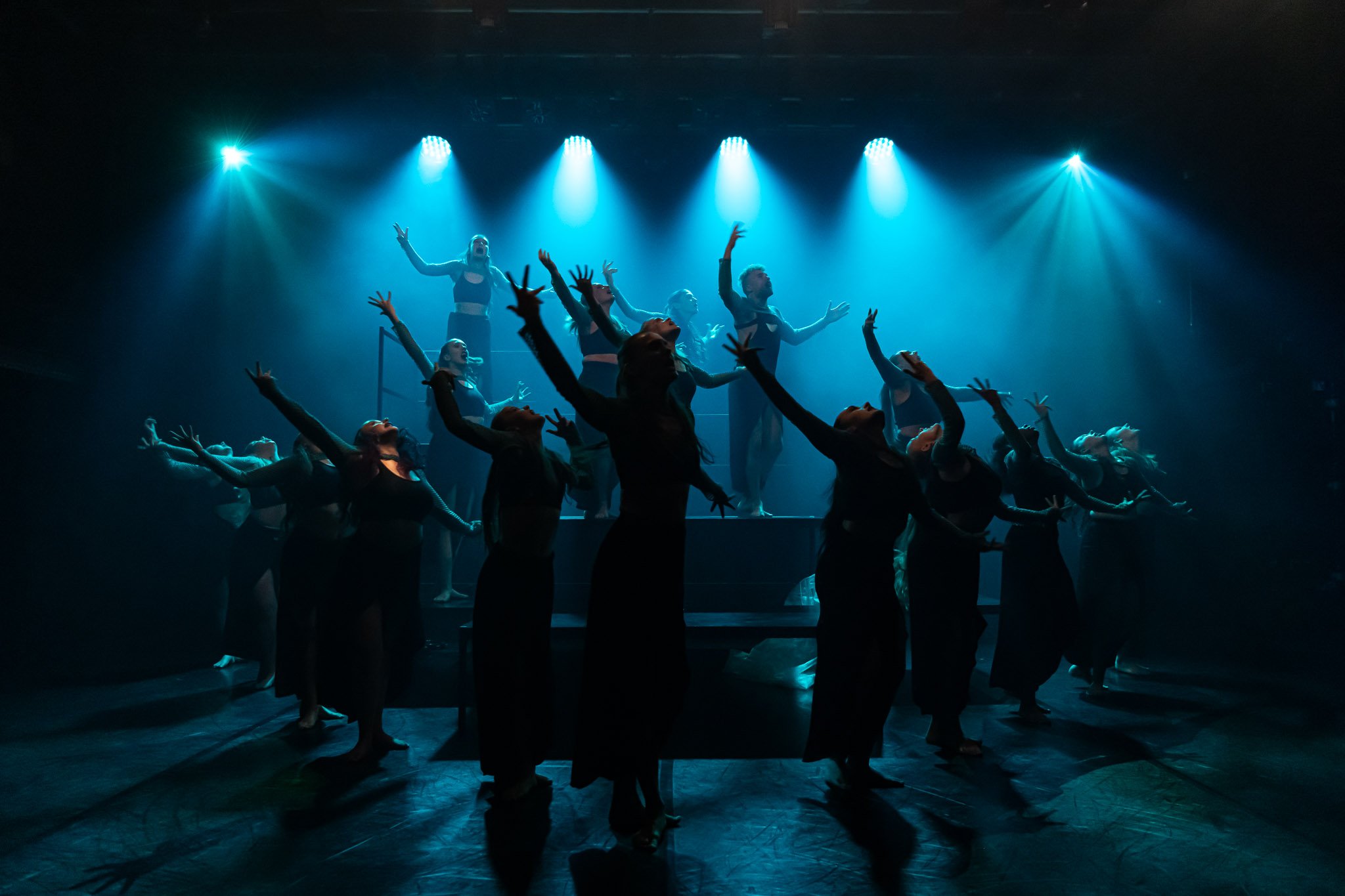Contemporary dance performance with dancers on stage, dramatic lighting
