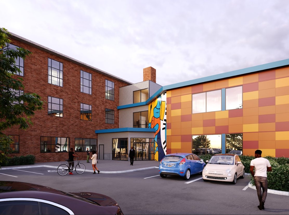 A modern building with a colorful mural on the front, parking lot with cars and people walking or talking outside, and a cloudy sky.