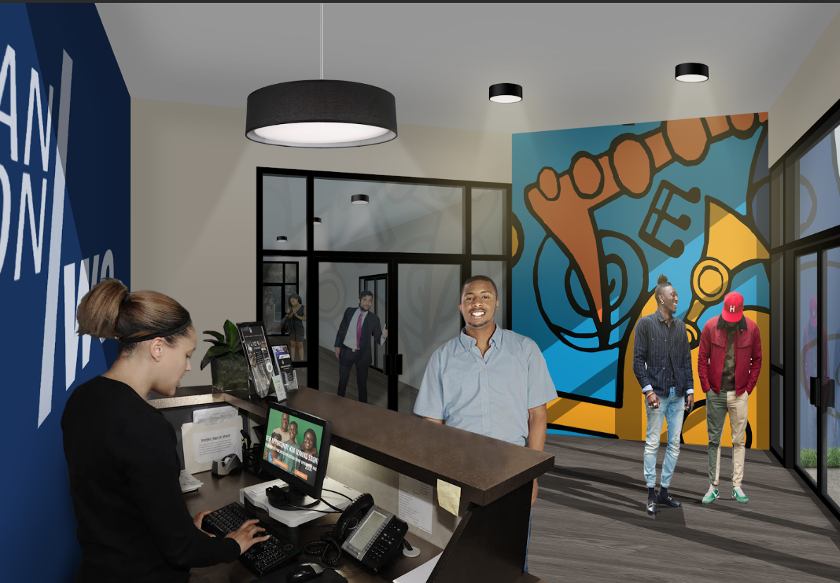 People in a modern office reception area with a colorful mural on the wall, a front desk with a staff member working on a computer, and several visitors standing and talking.