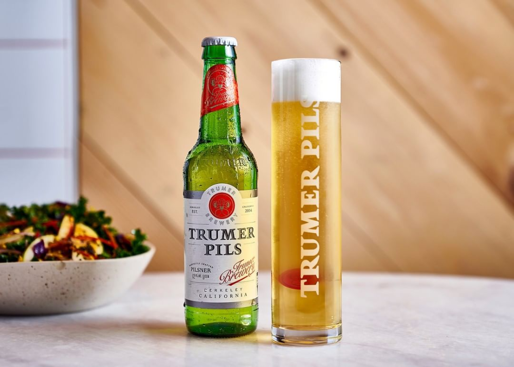 Trumer Pils bottle and glass on tabletop.